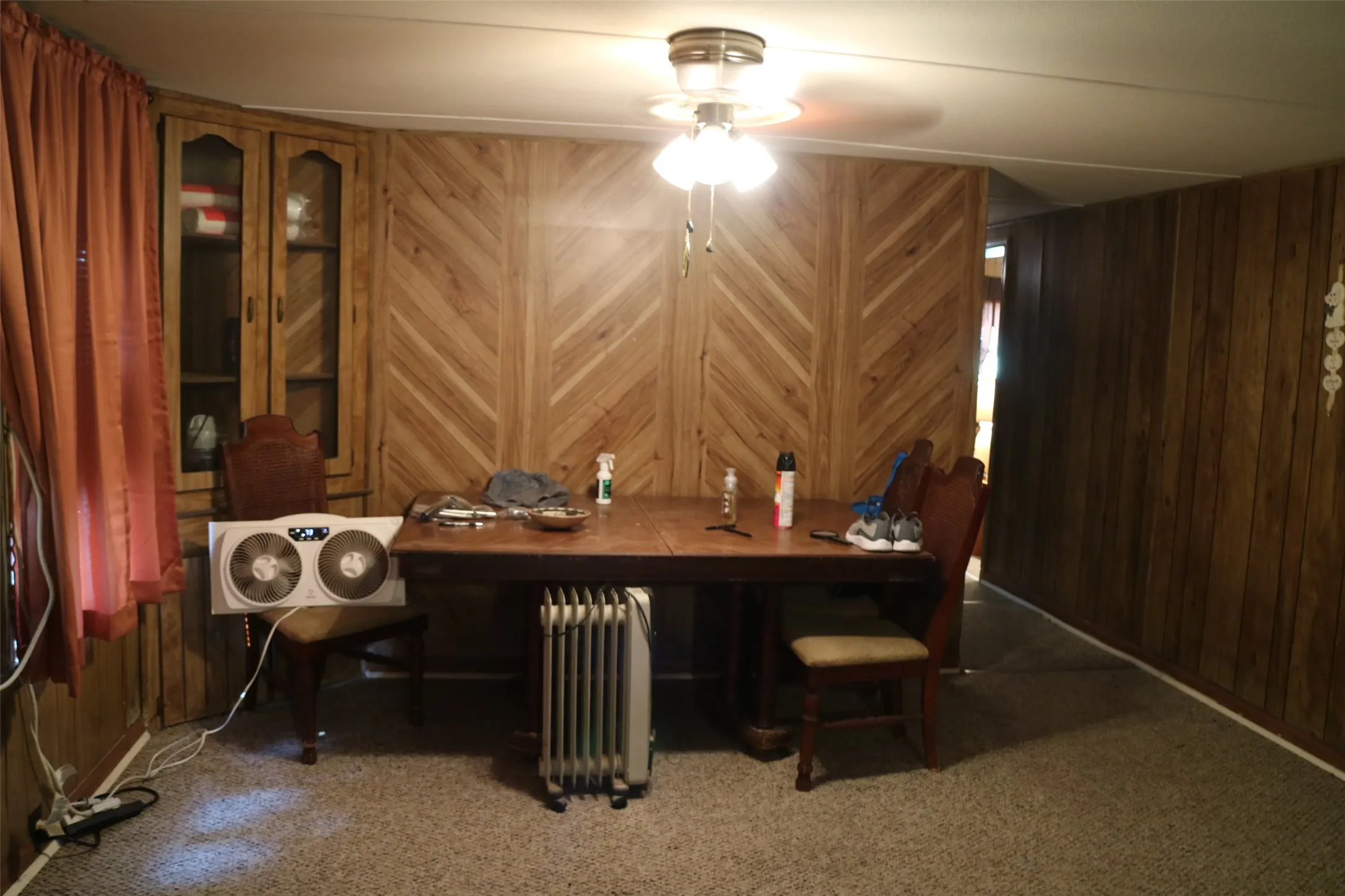 Carpeted dining space featuring radiator heating unit, wood walls, and ceiling fan
