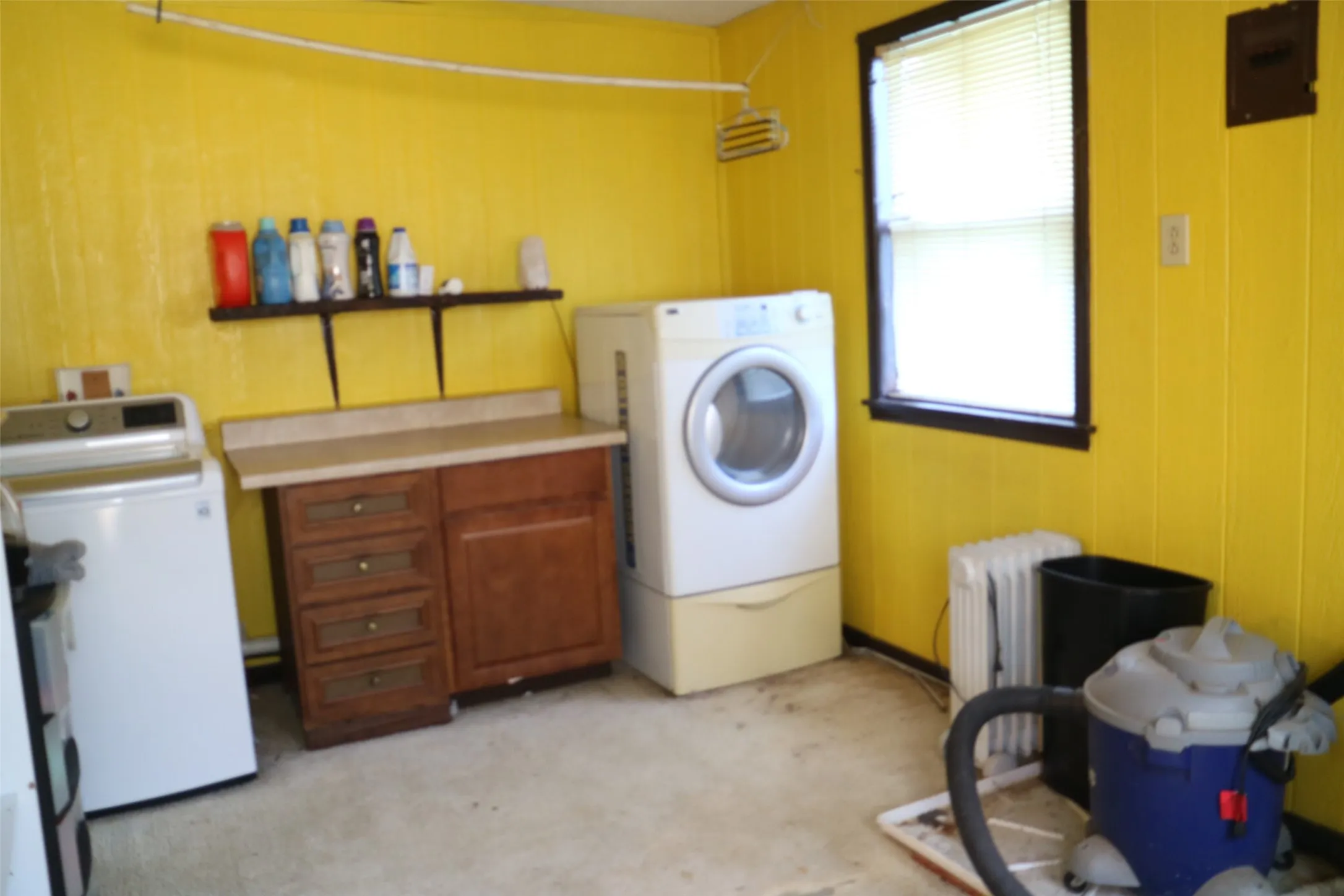 Washroom with radiator, independent washer and dryer, and wood walls