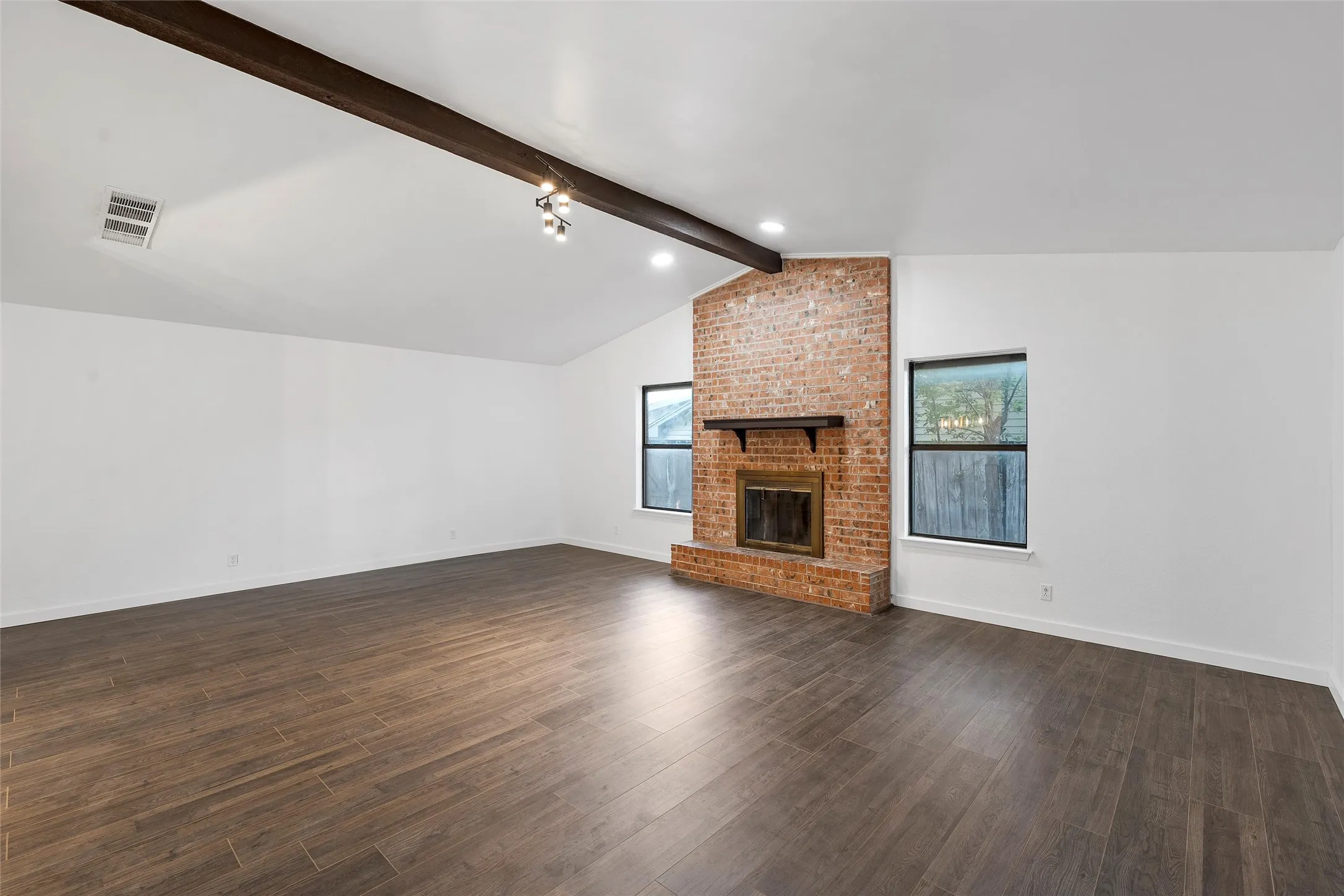 Unfurnished living room with a fireplace and dark wood-type flooring