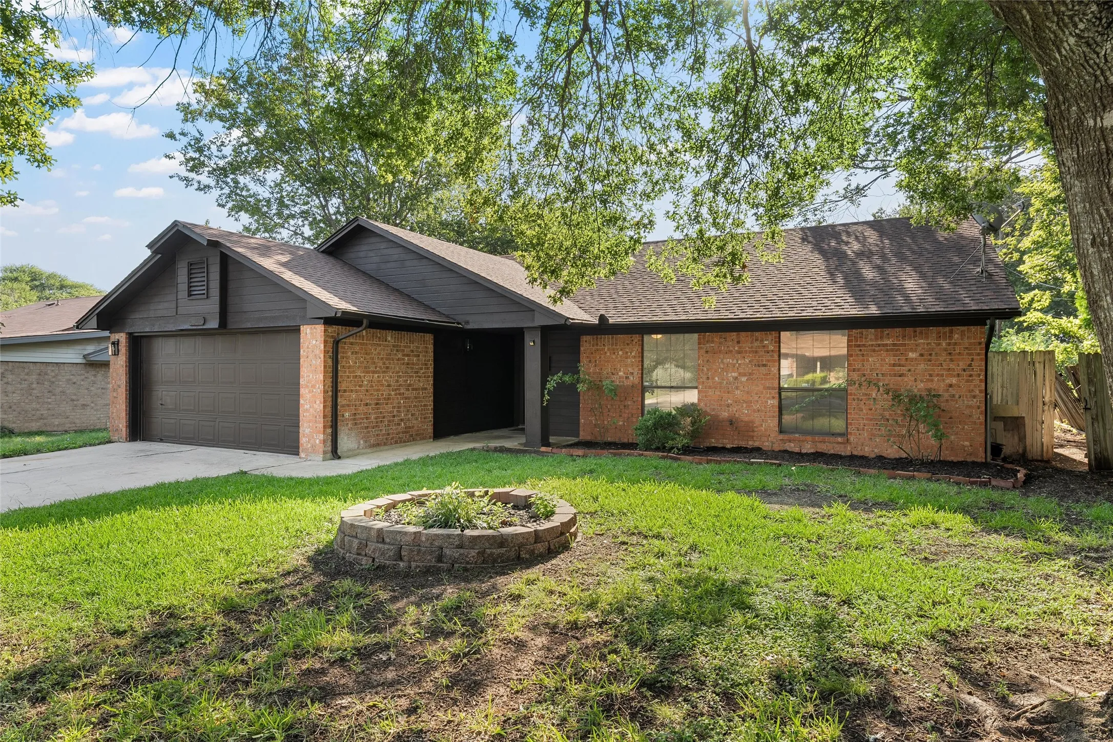 View of front of property with brick siding, roof with shingles, an attached garage, and concrete driveway