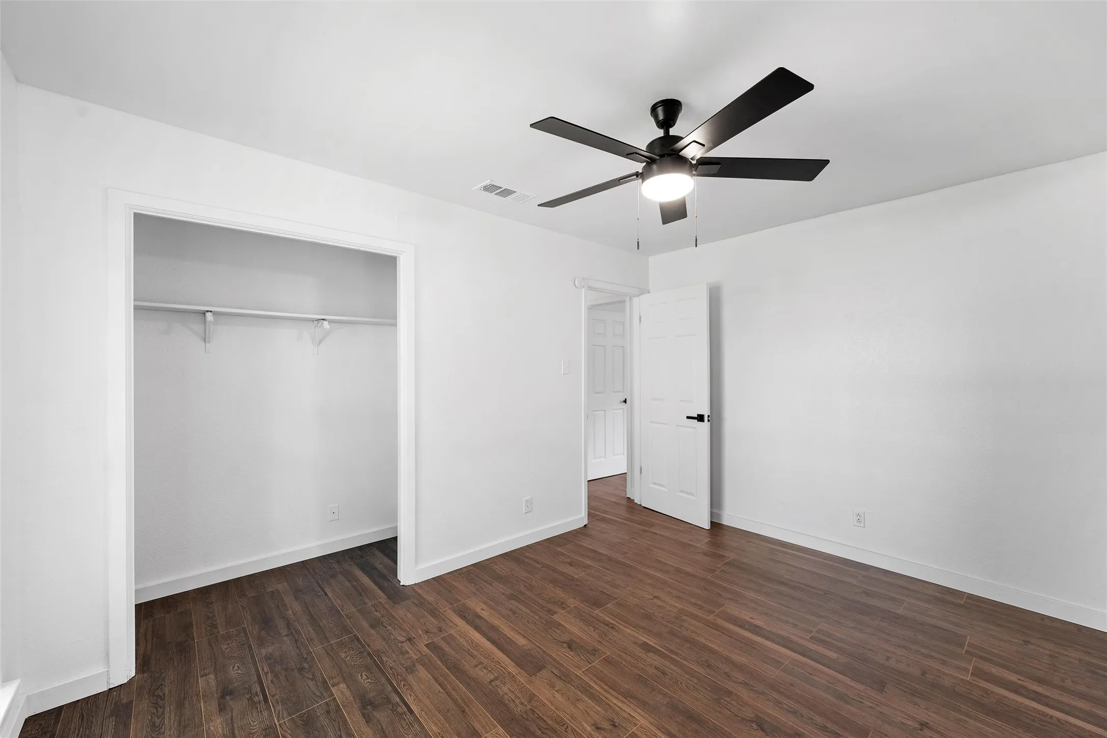 Unfurnished bedroom featuring dark wood-type flooring, ceiling fan, and a closet
