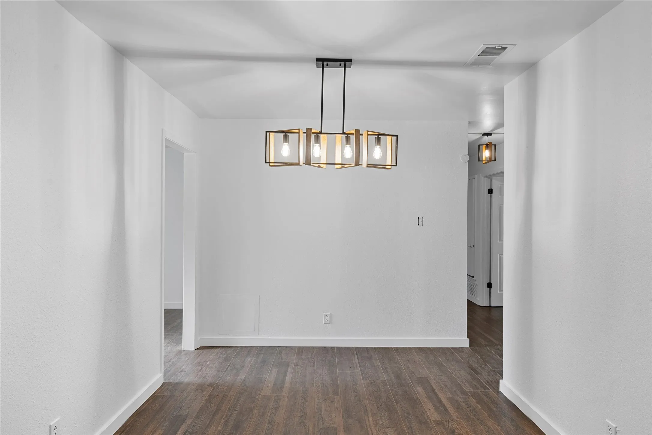 Unfurnished dining area featuring dark wood-style flooring and a chandelier