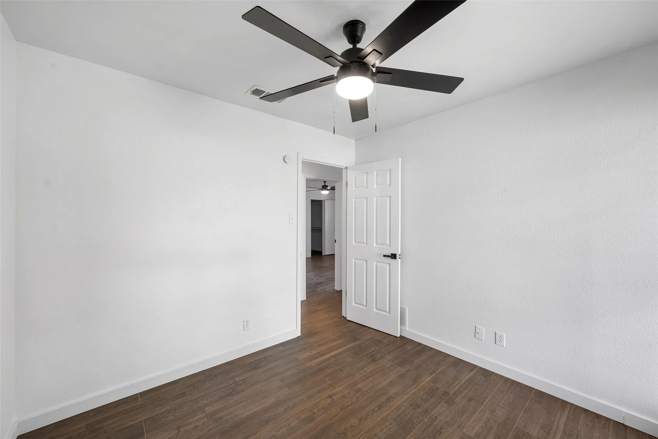 Unfurnished bedroom with dark wood-style flooring and ceiling fan