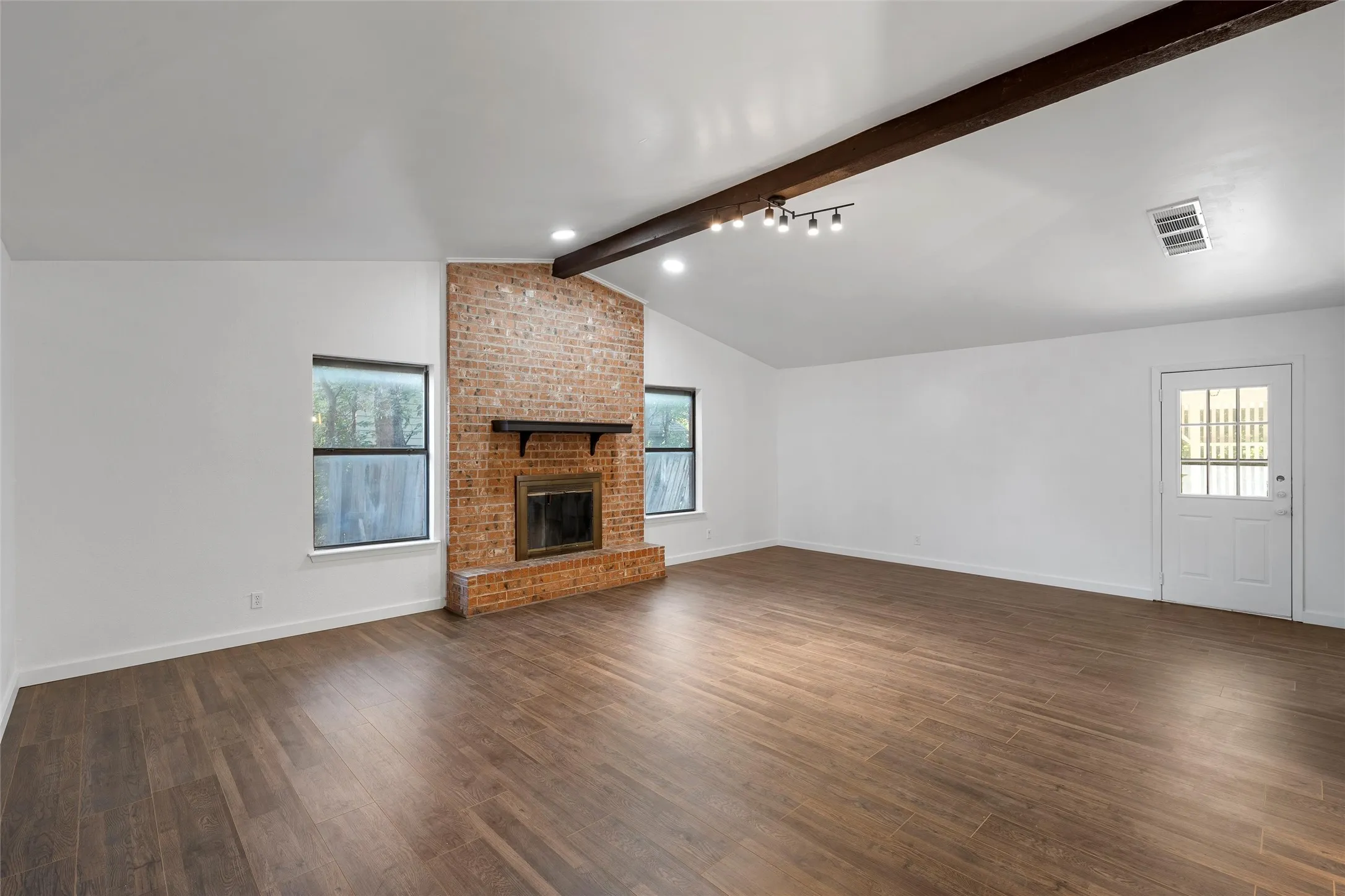 Unfurnished living room featuring healthy amount of natural light and dark wood-style flooring