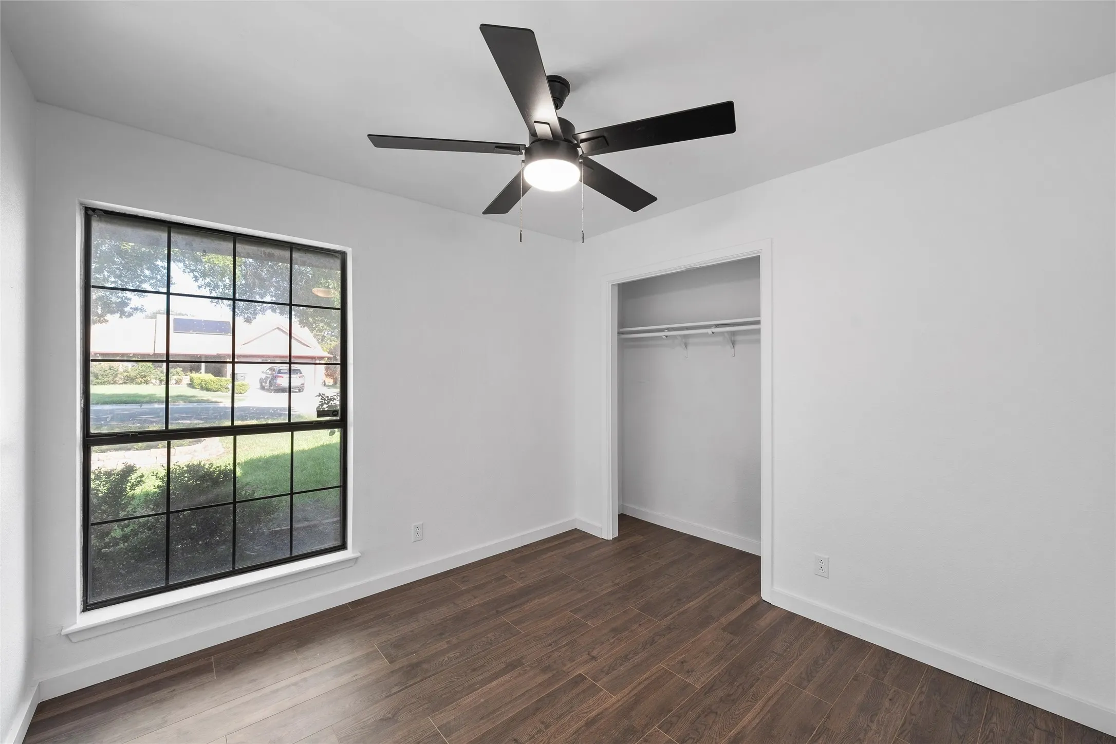 Unfurnished bedroom with dark wood-style flooring, ceiling fan, and a closet