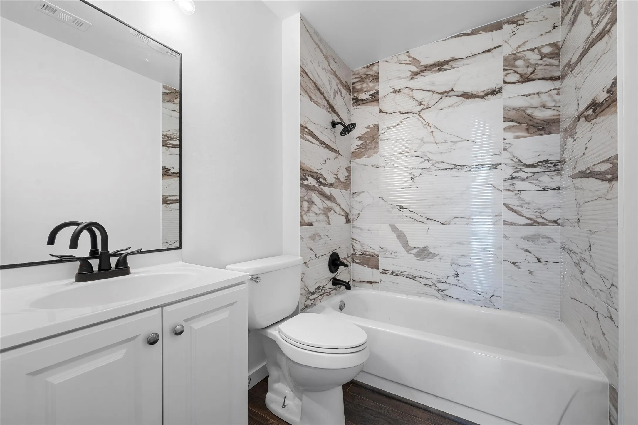 Full bath with tub / shower combination, vanity, and dark wood-type flooring