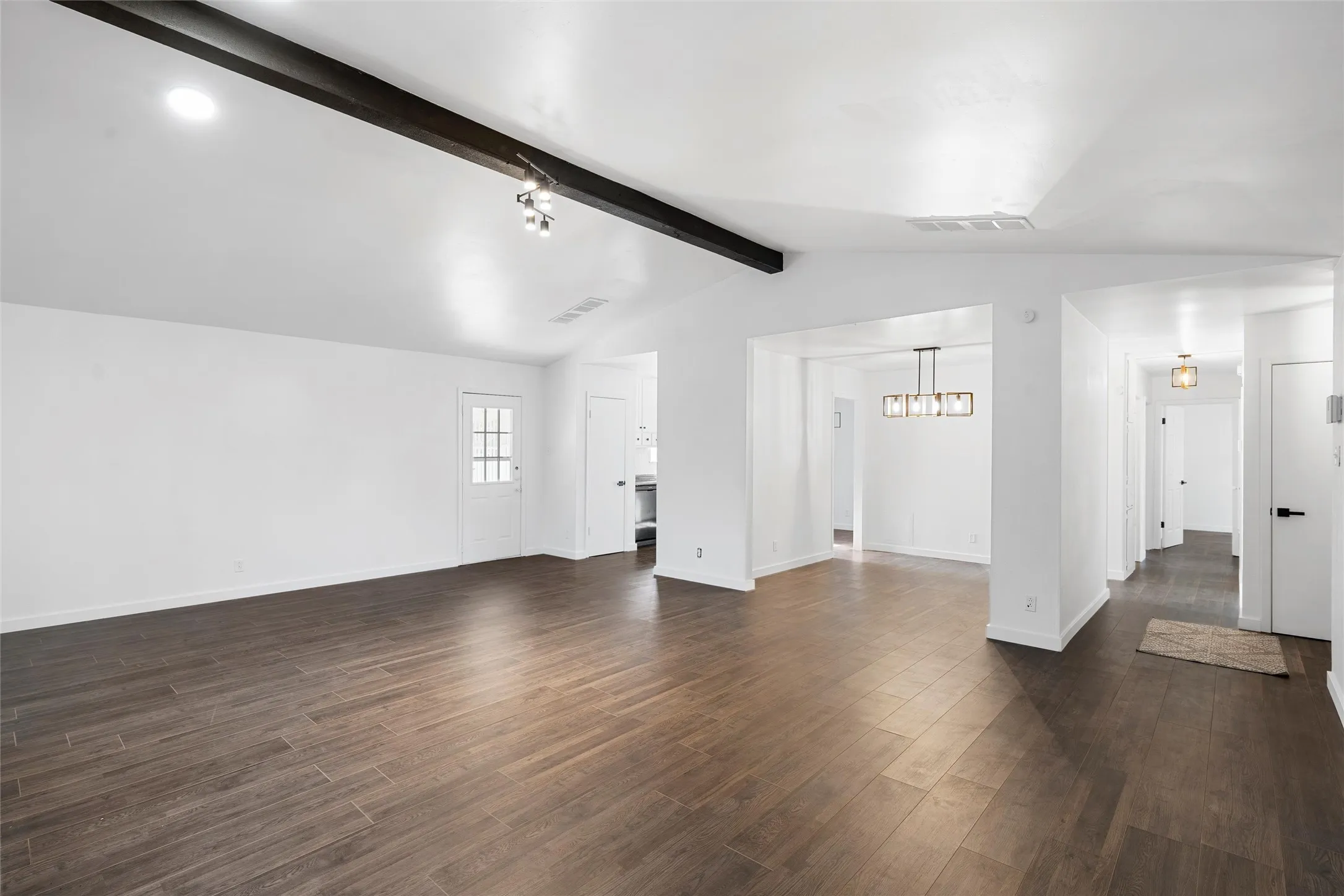 Unfurnished living room with dark wood-style flooring and a chandelier