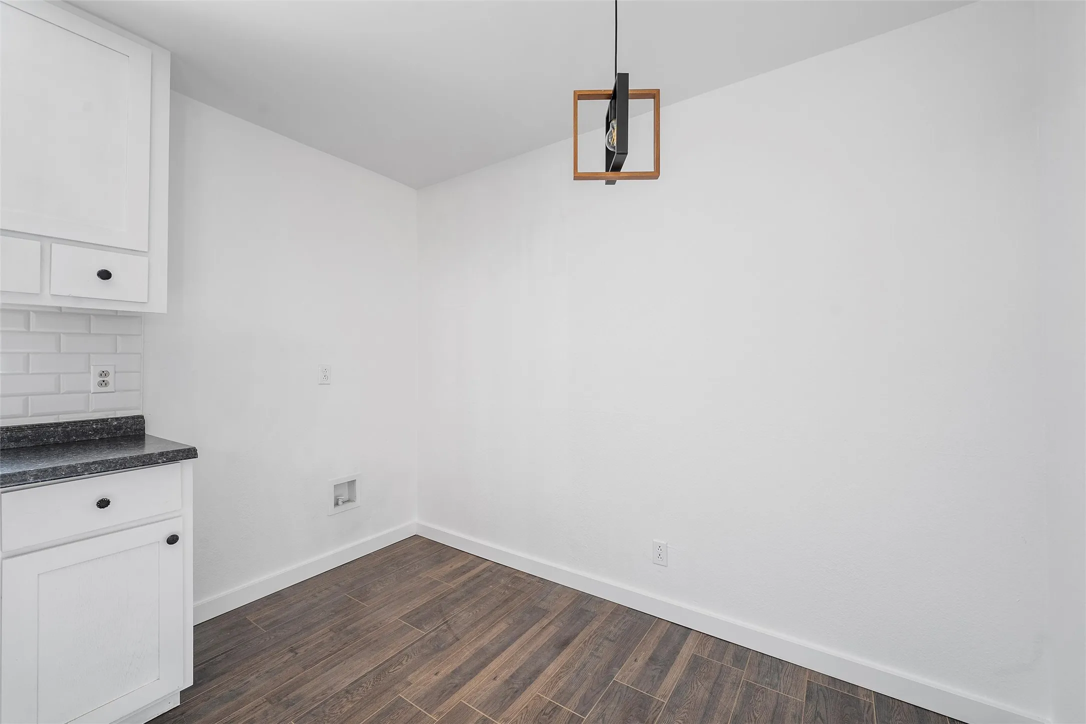 Unfurnished dining area with dark wood-style floors and baseboards