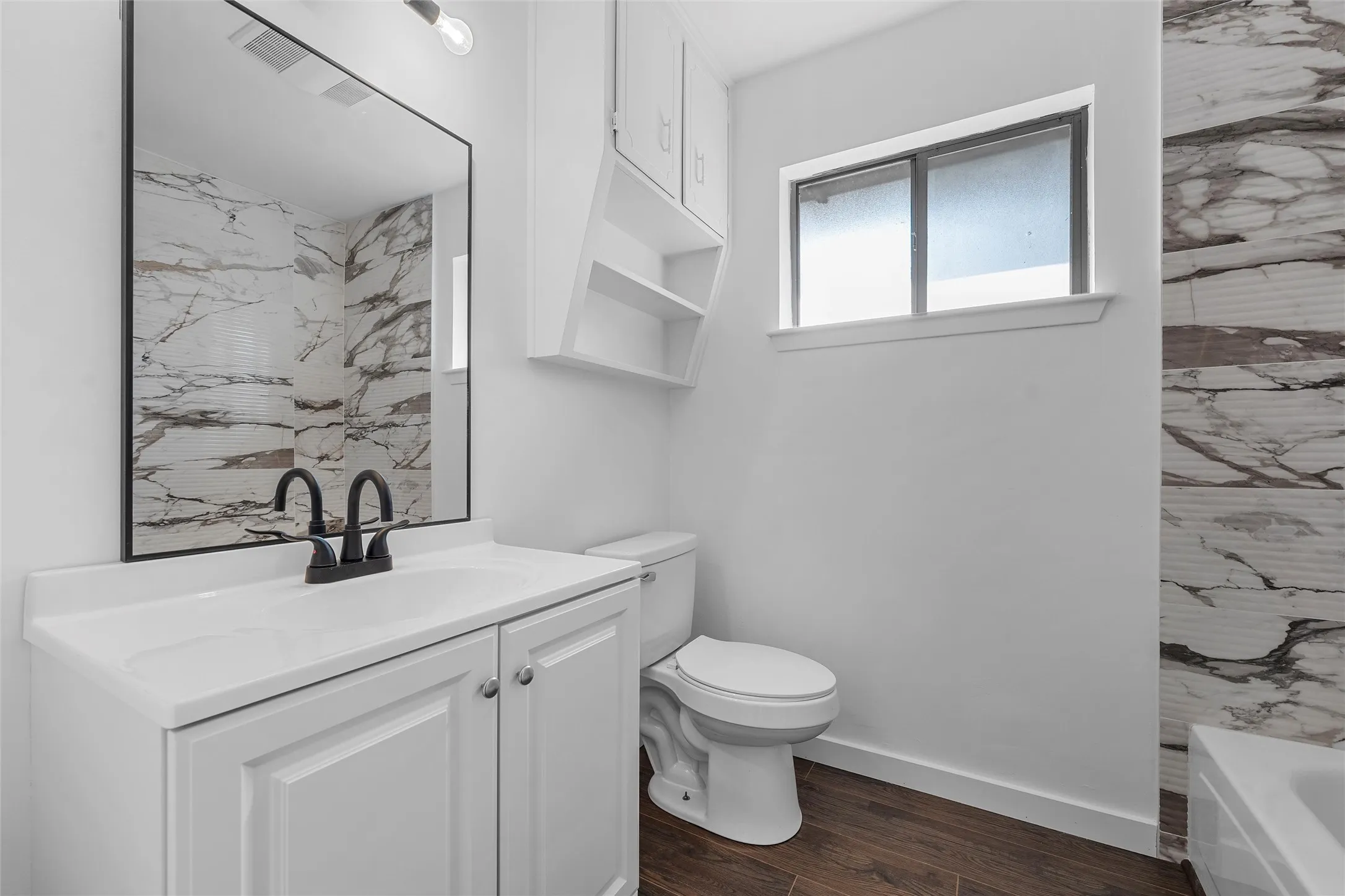 Full bath with vanity and dark wood-type flooring