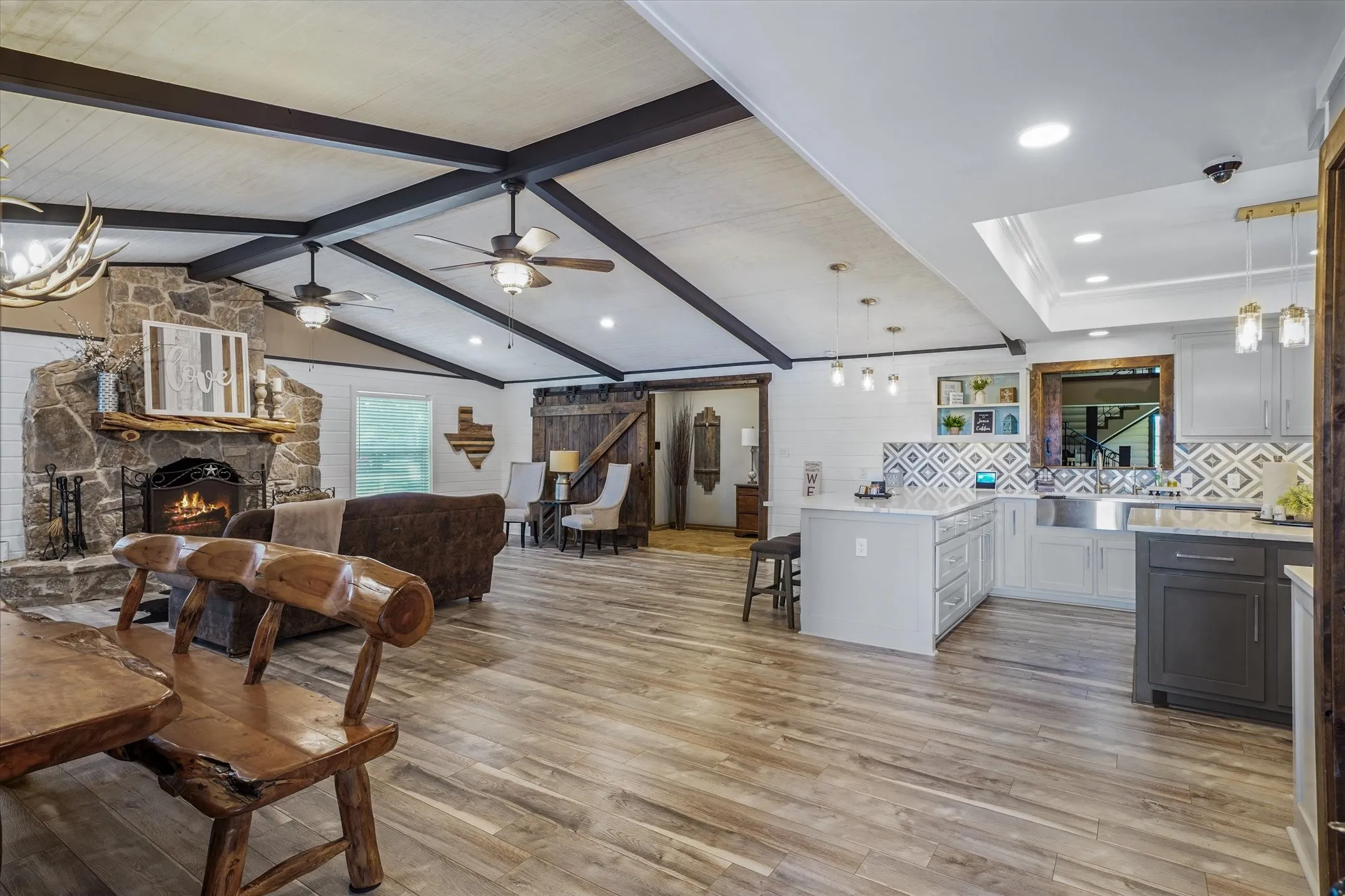 Living room featuring light wood-style floors, a chandelier, a stone fireplace, and recessed lighting