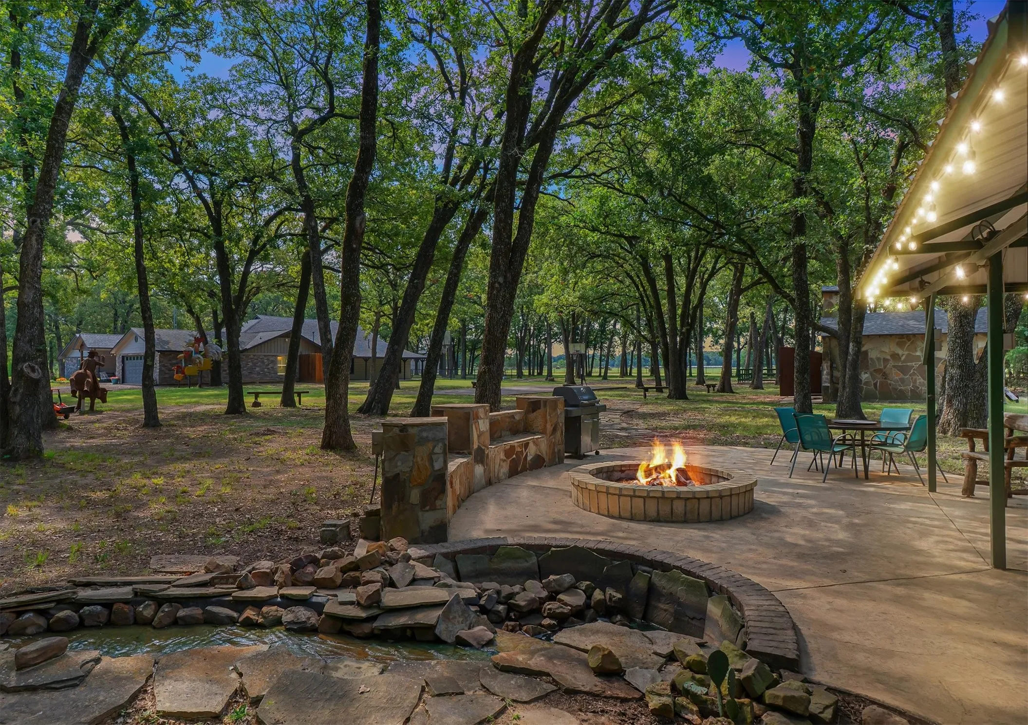 View of patio with a small pond, an outdoor fire pit, view of scattered trees, and area for grilling