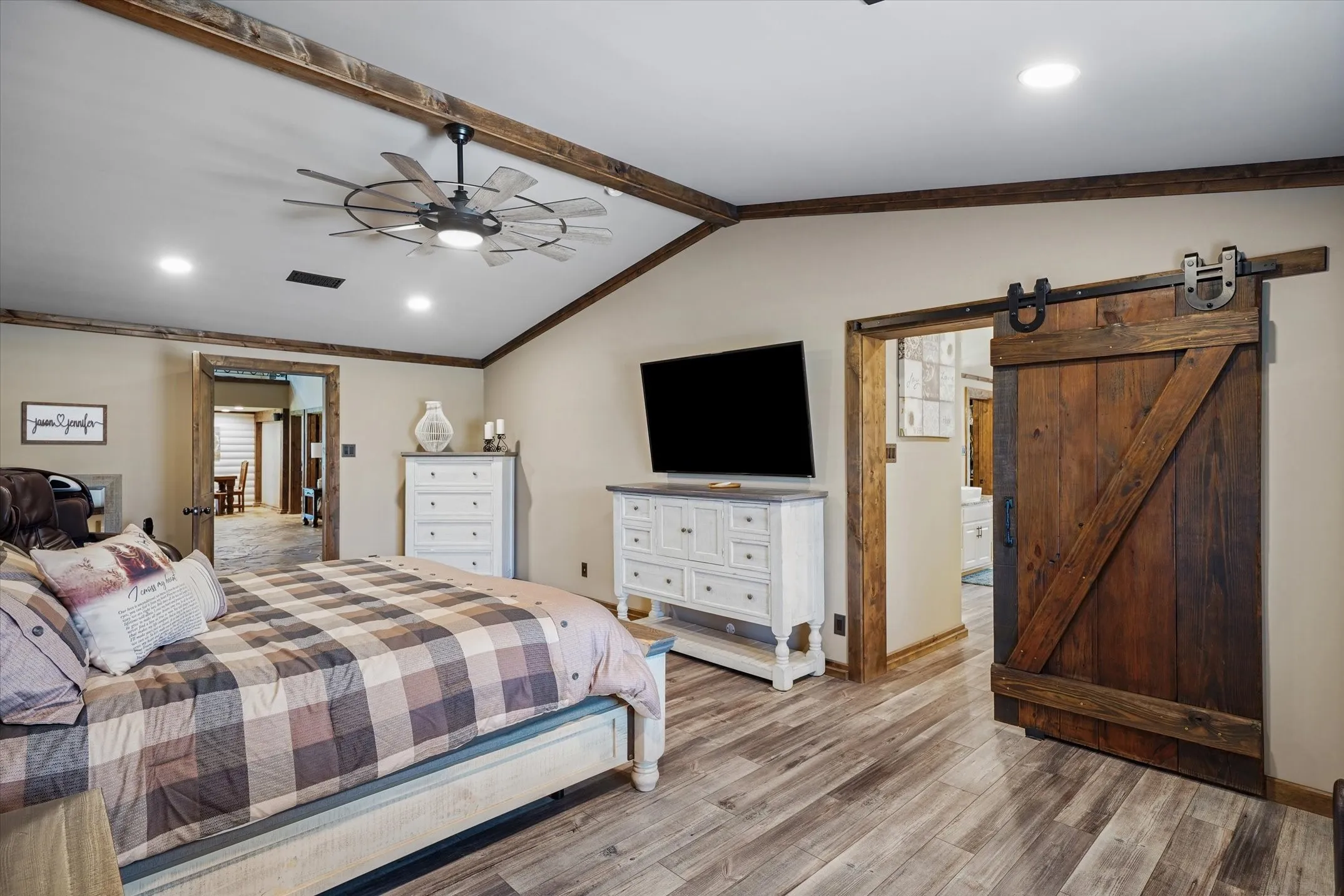 Bedroom with a barn door, crown molding, wood finished floors, recessed lighting, and ceiling fan