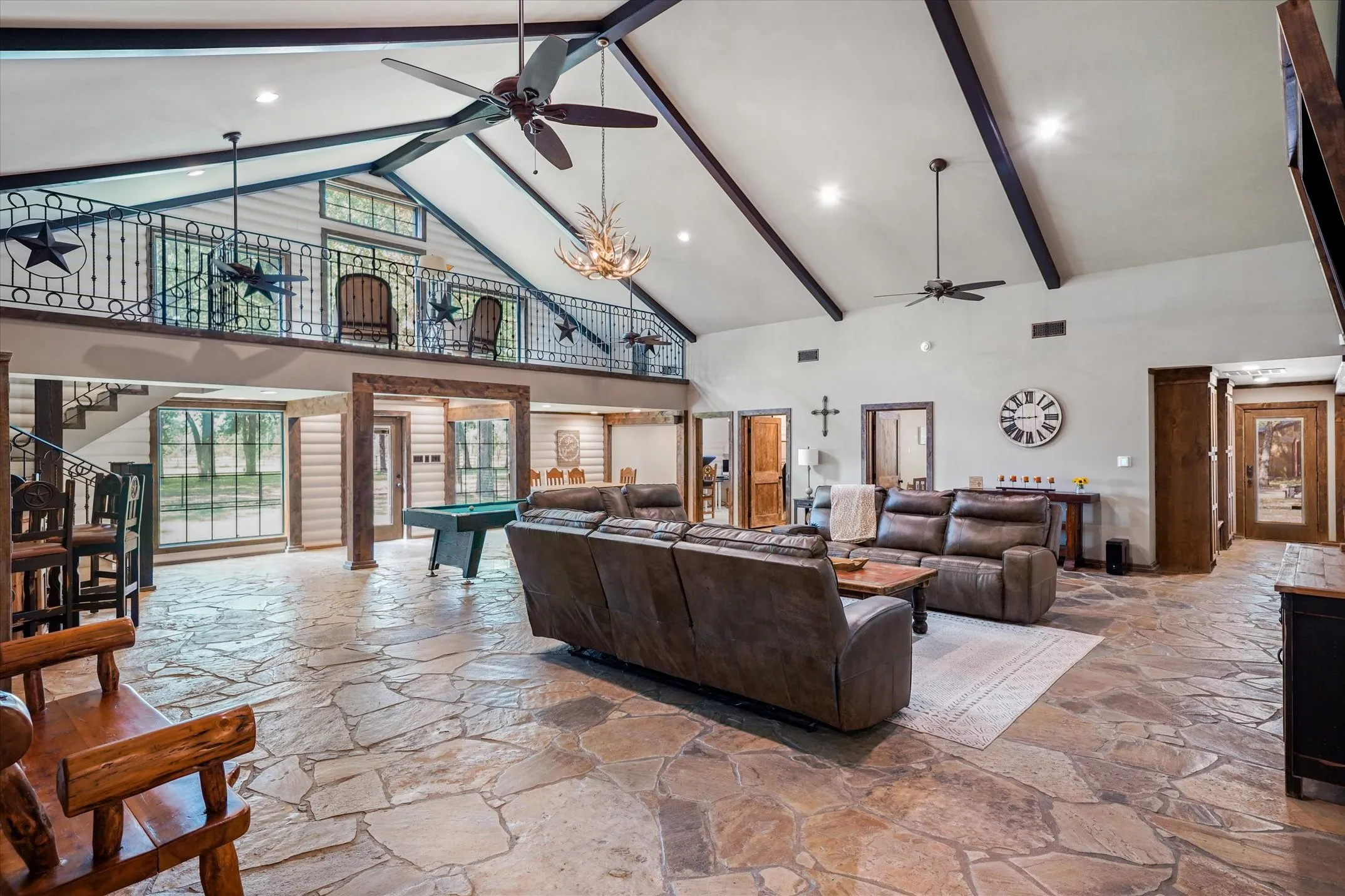Living room with high vaulted ceiling, beam ceiling, ceiling fan, stone tile flooring, and pool table