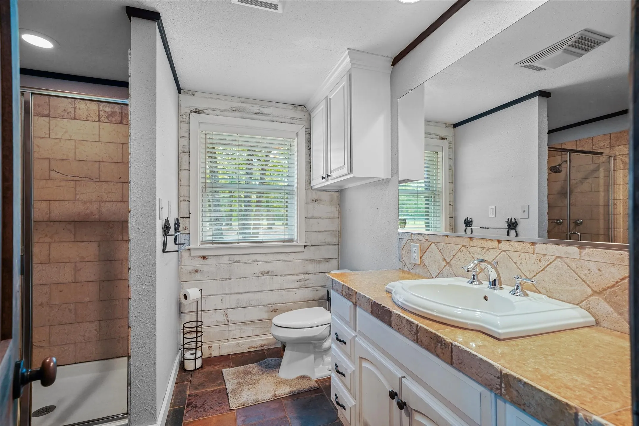 Full bath featuring a shower stall, vanity, and tasteful backsplash