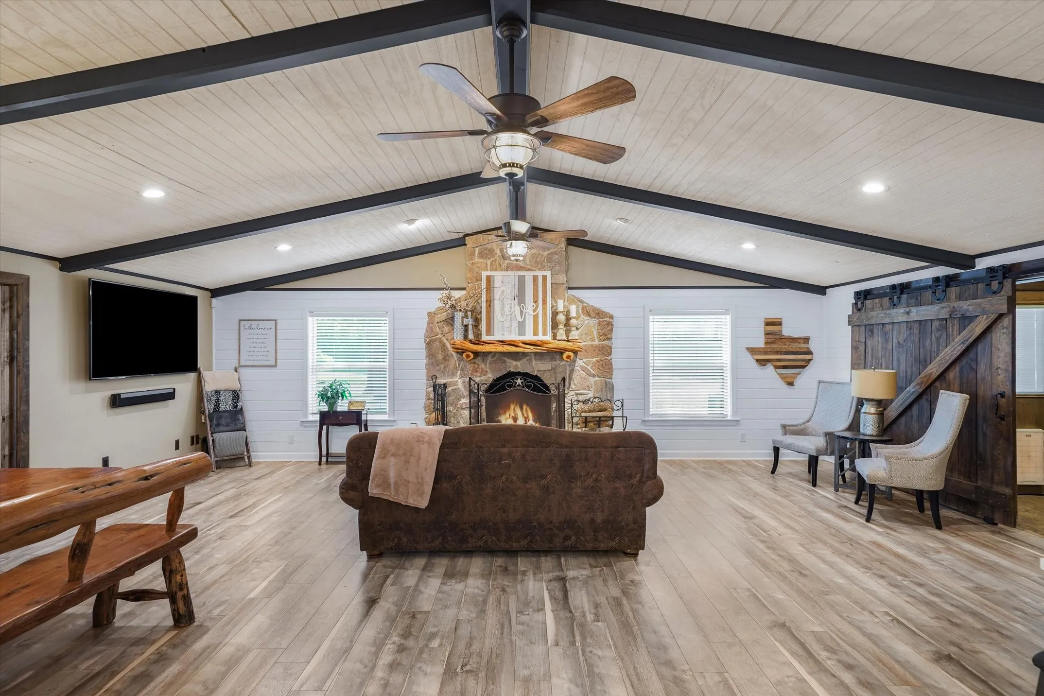Living room featuring a barn door, plenty of natural light, light wood-style flooring, recessed lighting, and wooden walls
