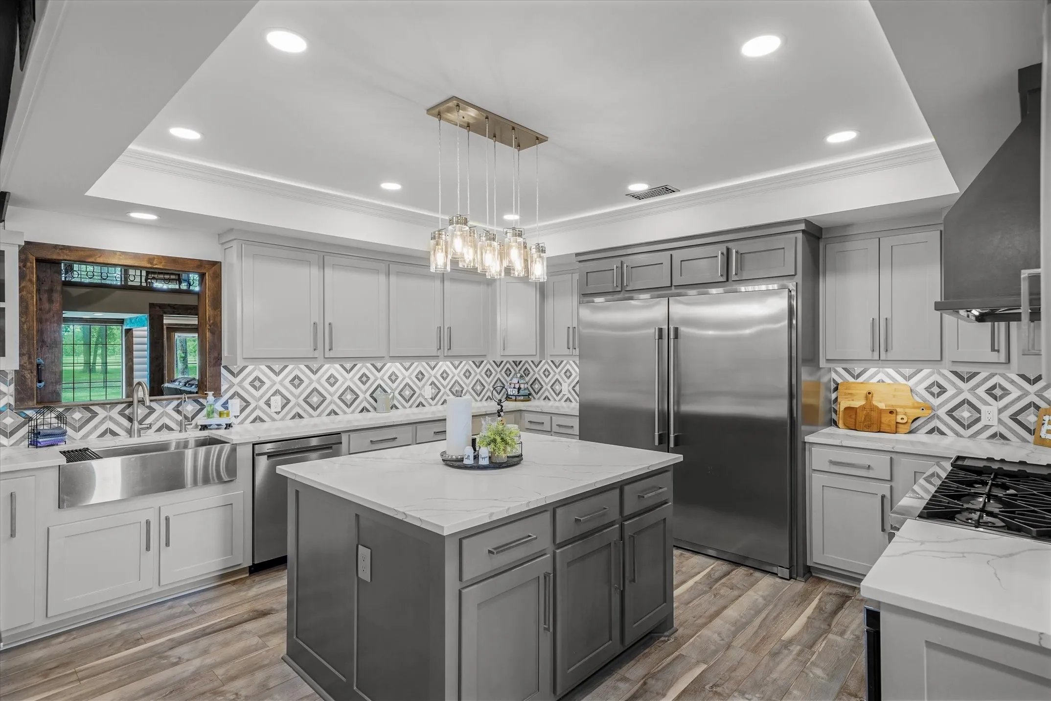 Kitchen with gray cabinets, decorative backsplash, recessed lighting, light stone counters, and a kitchen island