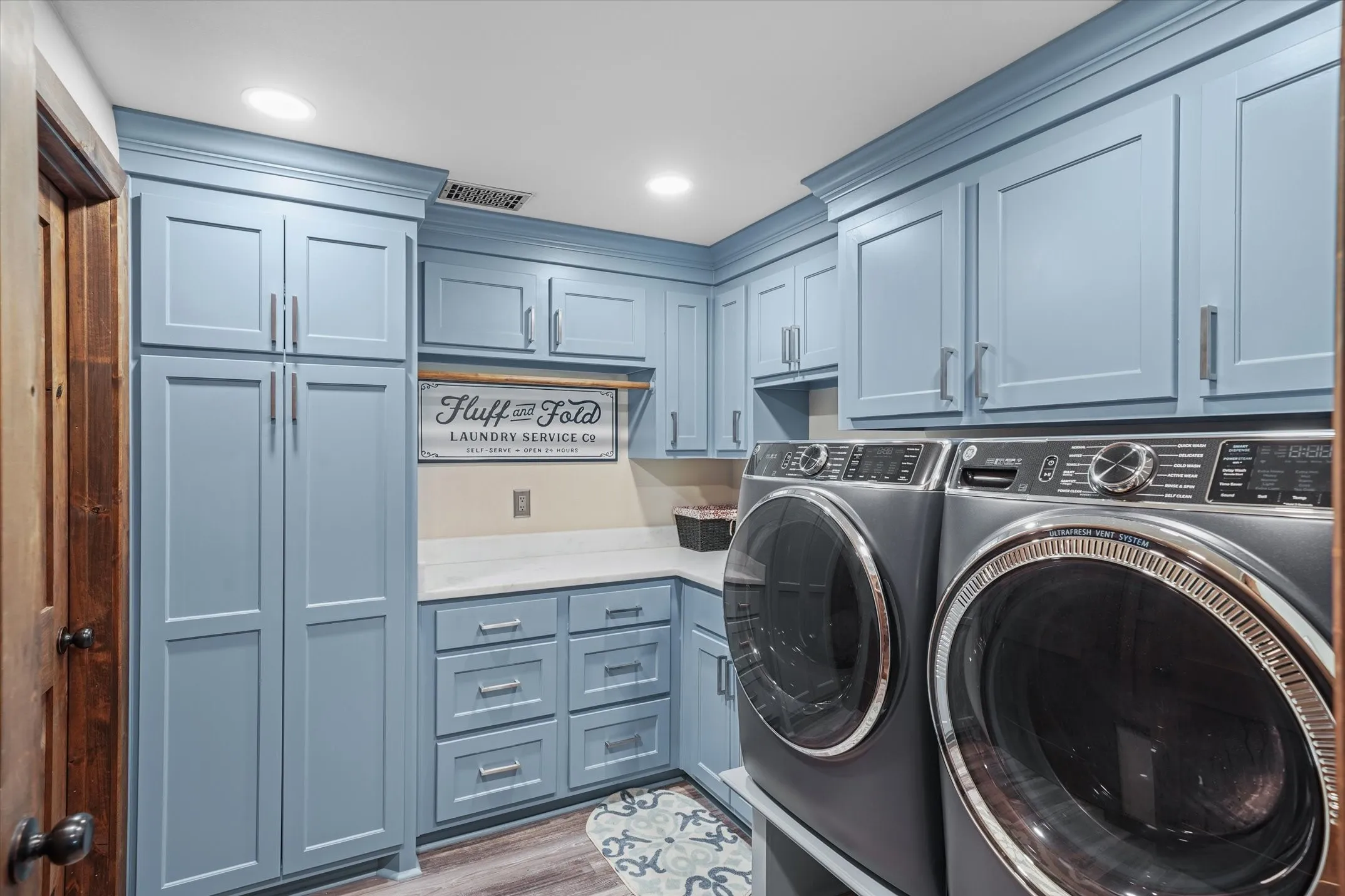 Washroom featuring light wood finished floors, cabinet space, recessed lighting, and washing machine and dryer