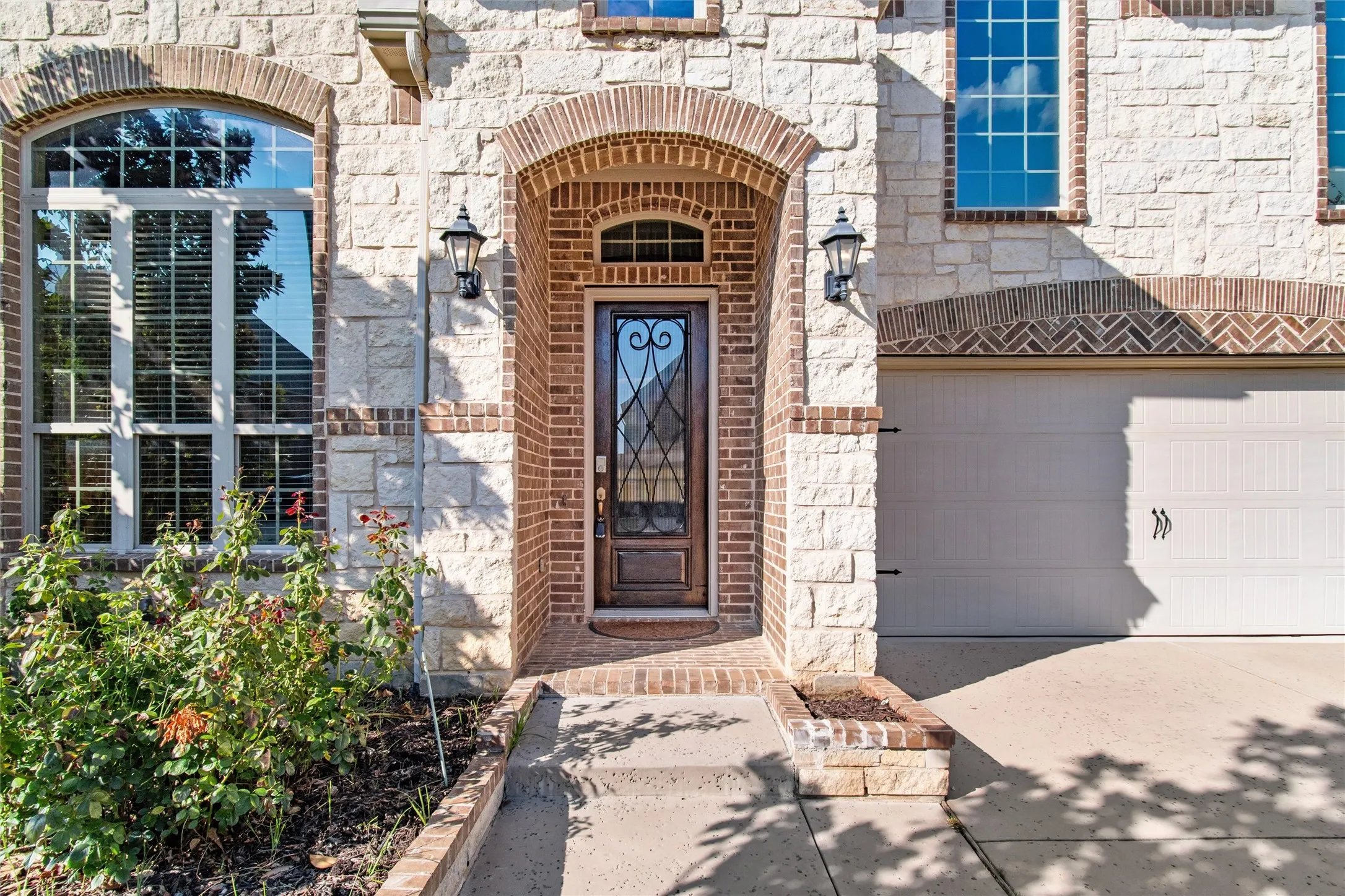 Property entrance with stone siding, brick siding, driveway, and an attached garage