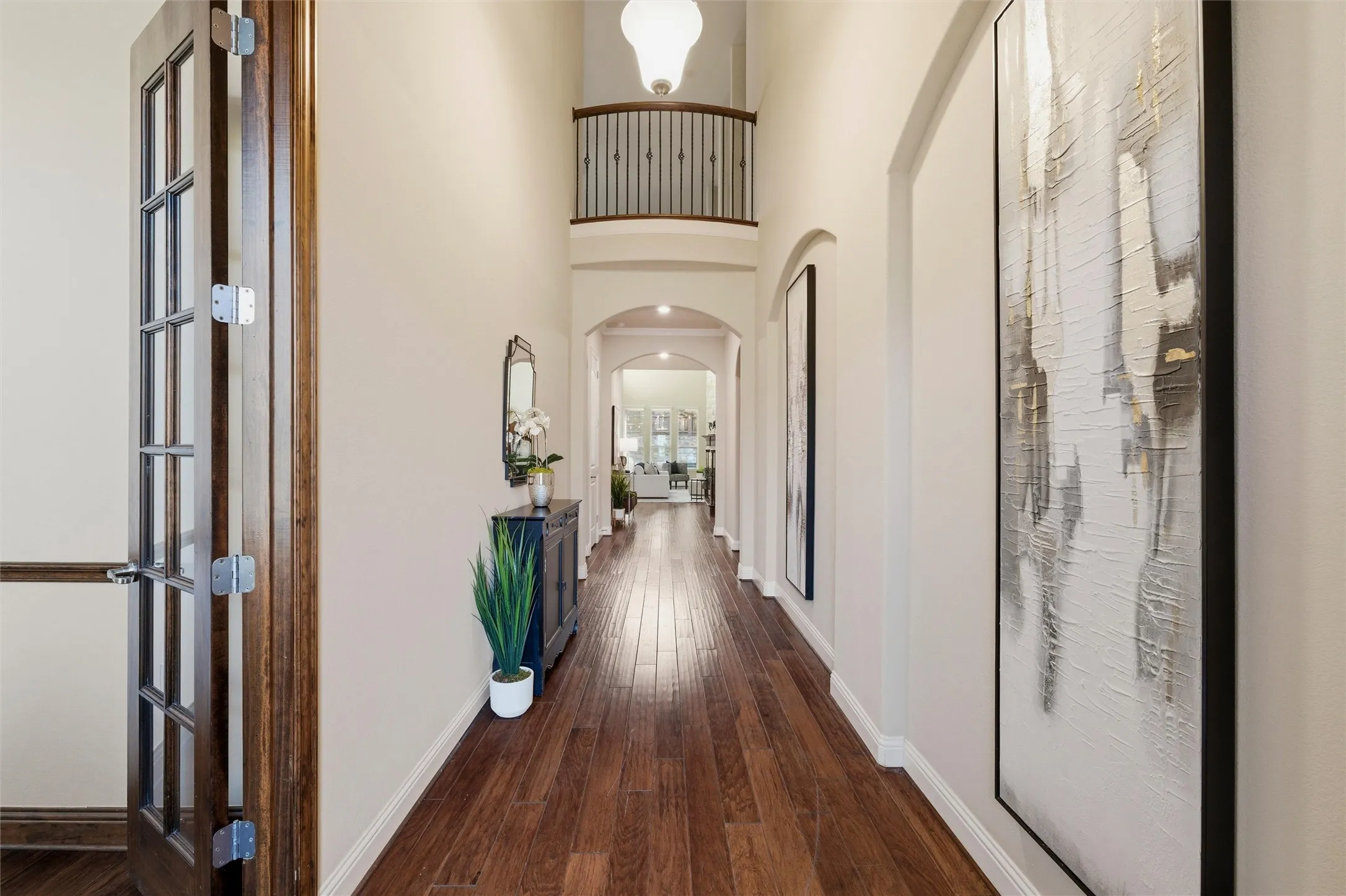 Upon entering, you are greeted by hand-scraped wood floors and a stunning arched hallway featuring a Juliette balcony.