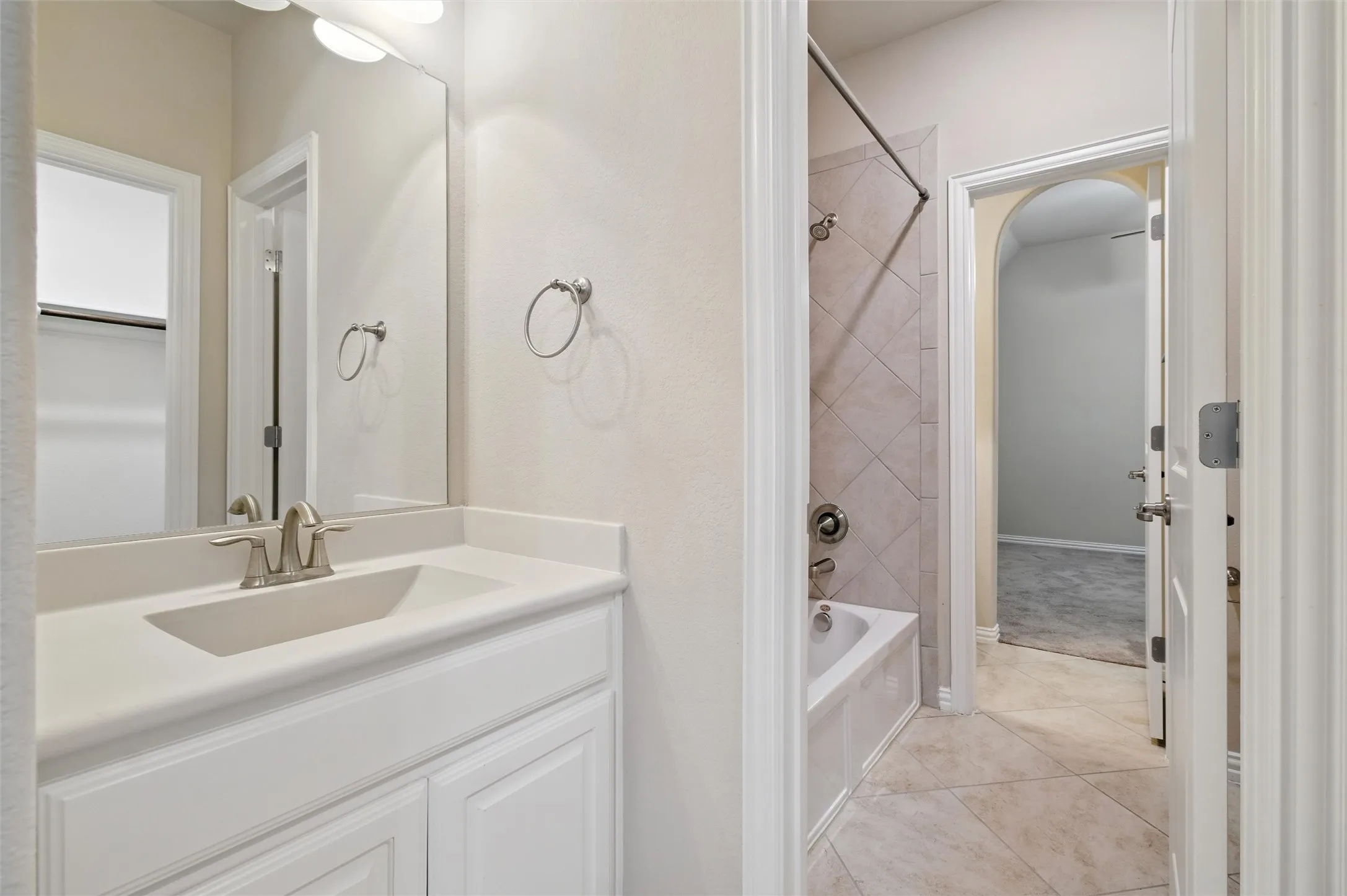 Bathroom with bathtub / shower combination, vanity, light tile patterned floors, and a closet