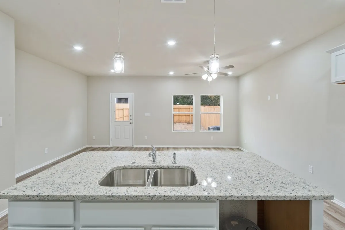 Kitchen featuring light stone counters, light wood-type flooring, recessed lighting, decorative light fixtures, and ceiling fan