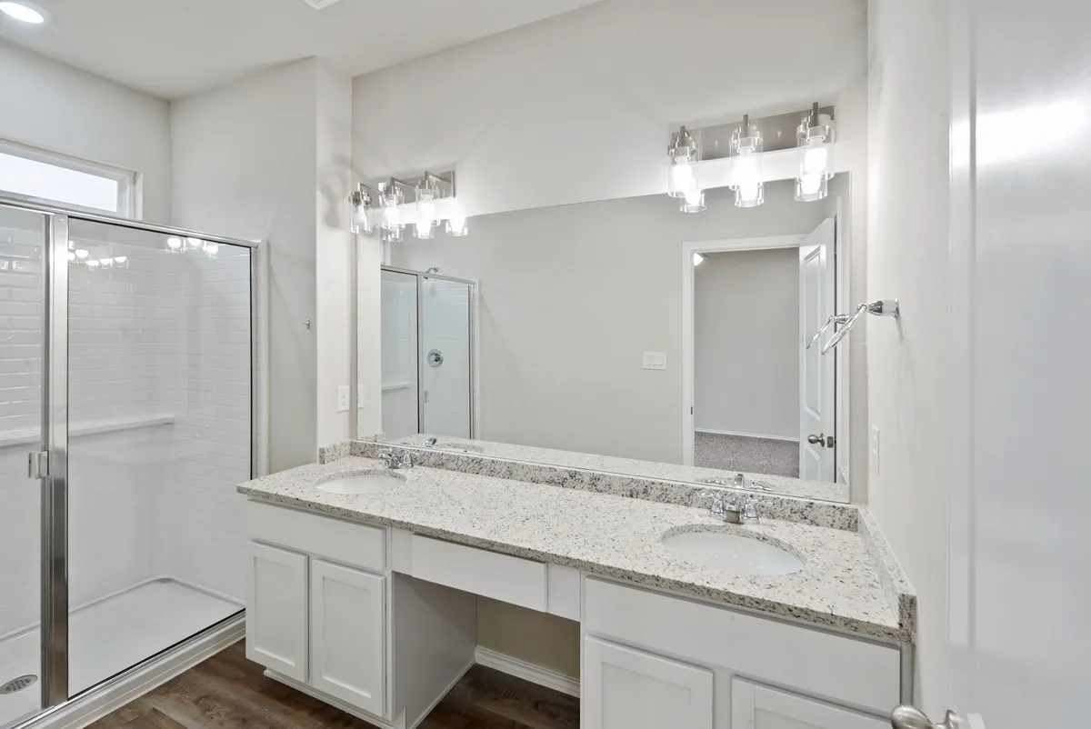 Full bathroom with a stall shower, double vanity, and dark wood finished floors