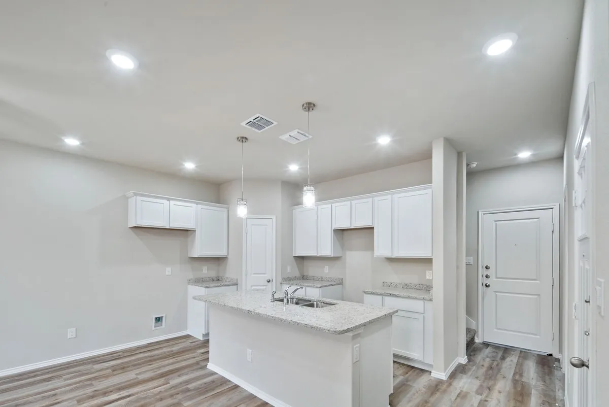 Kitchen featuring light wood-style floors, white cabinetry, a center island with sink, recessed lighting, and light stone counters
