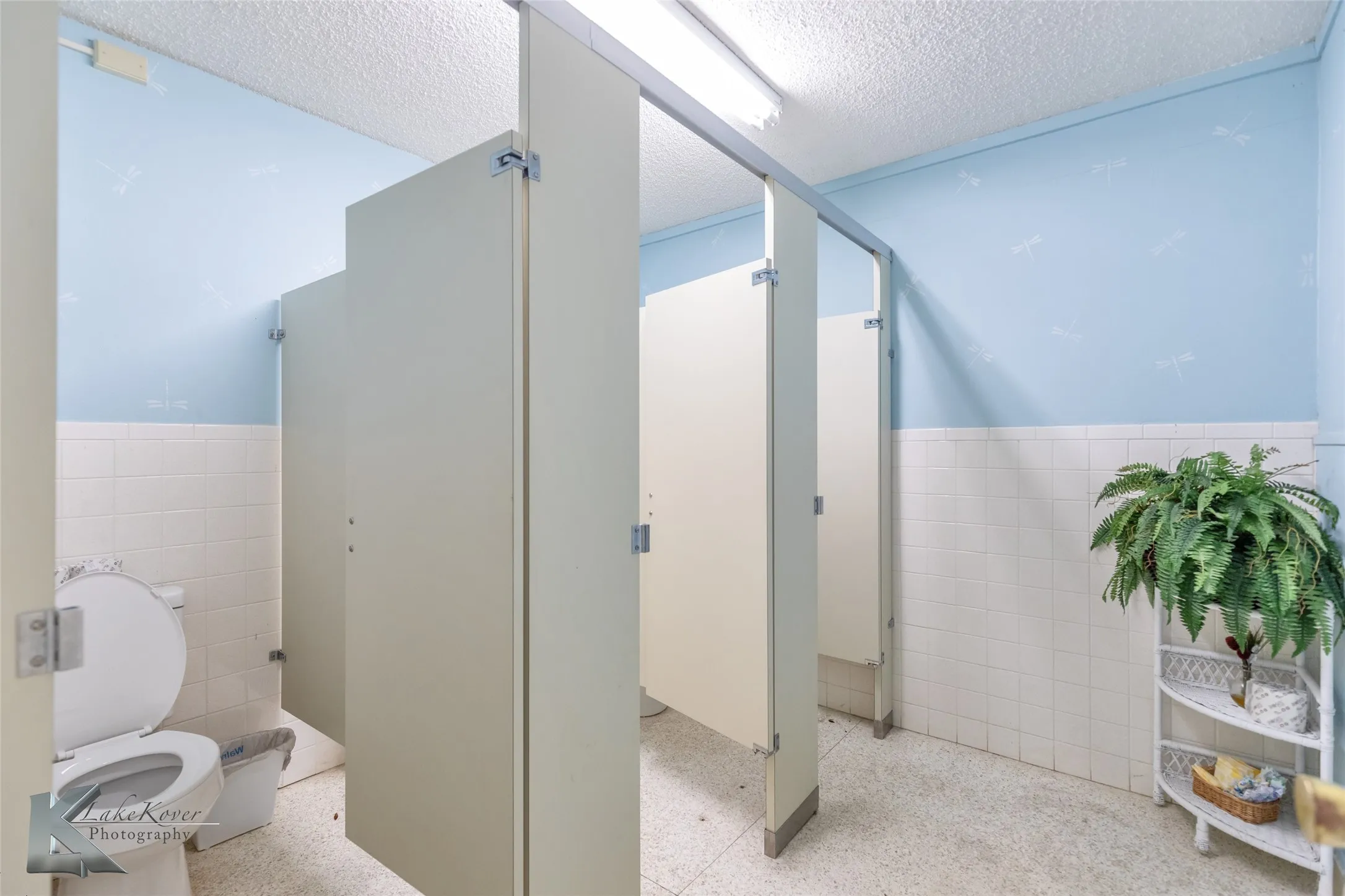 Bathroom featuring tile walls, a wainscoted wall, dark aggregate flooring, and a textured ceiling