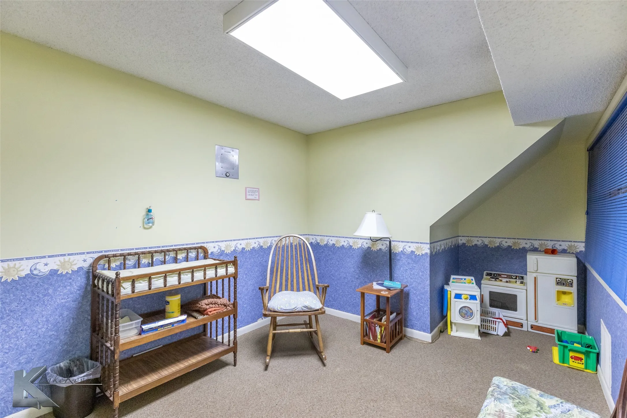 Game room with a textured ceiling, carpet floors, wallpapered walls, and a wainscoted wall