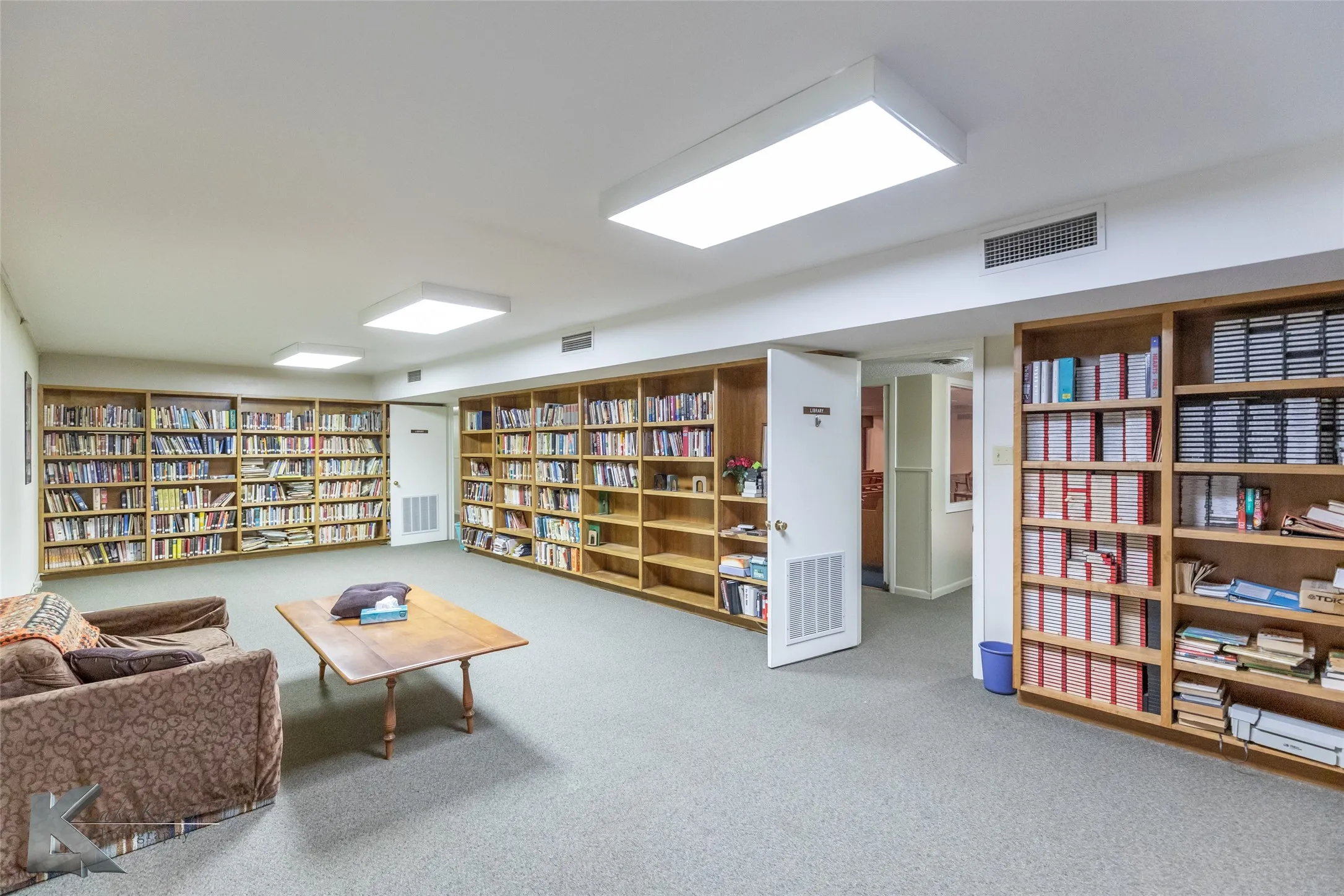 Sitting room featuring wall of books and carpet floors