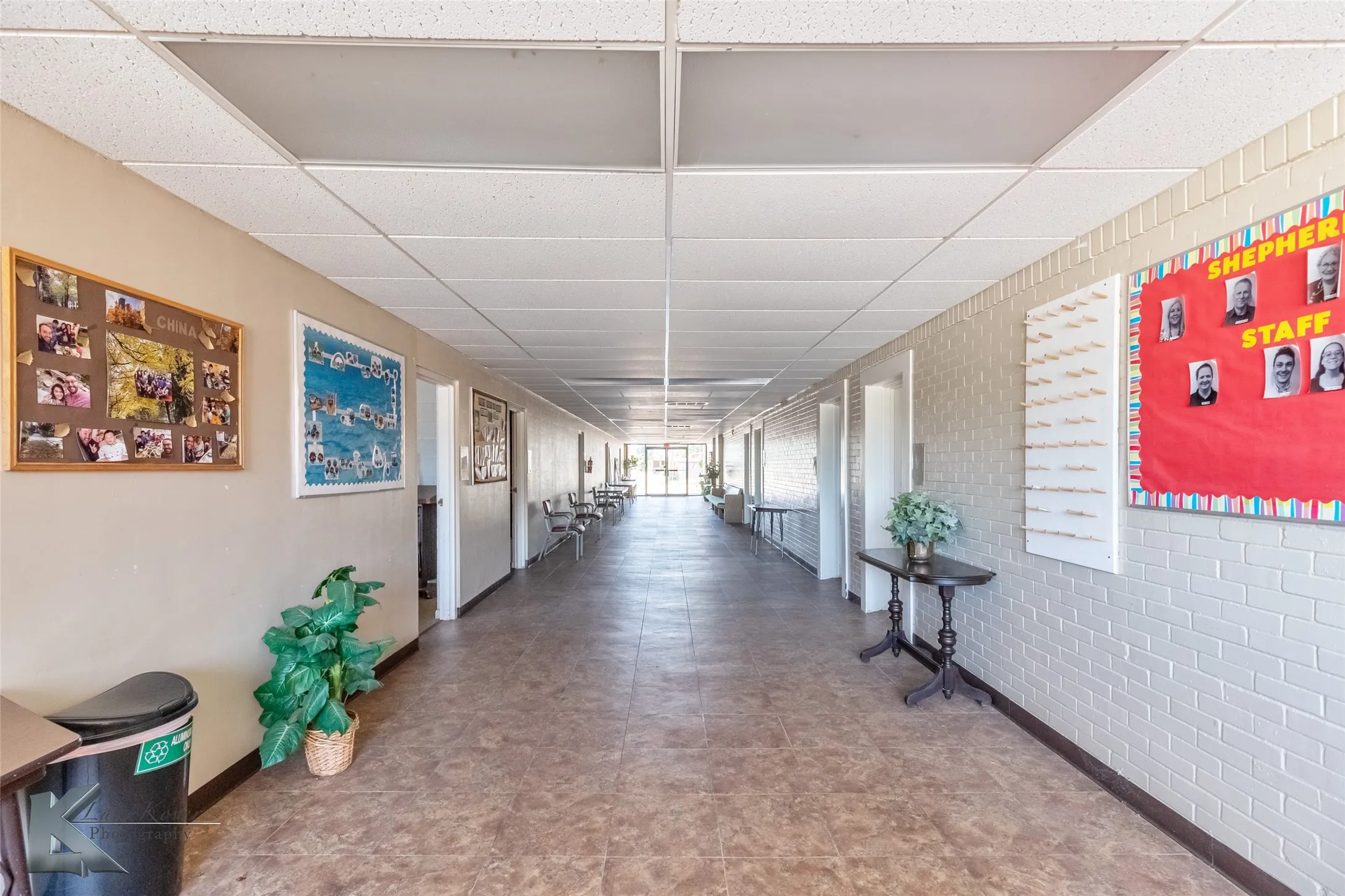 Hallway with a paneled ceiling and brick wall