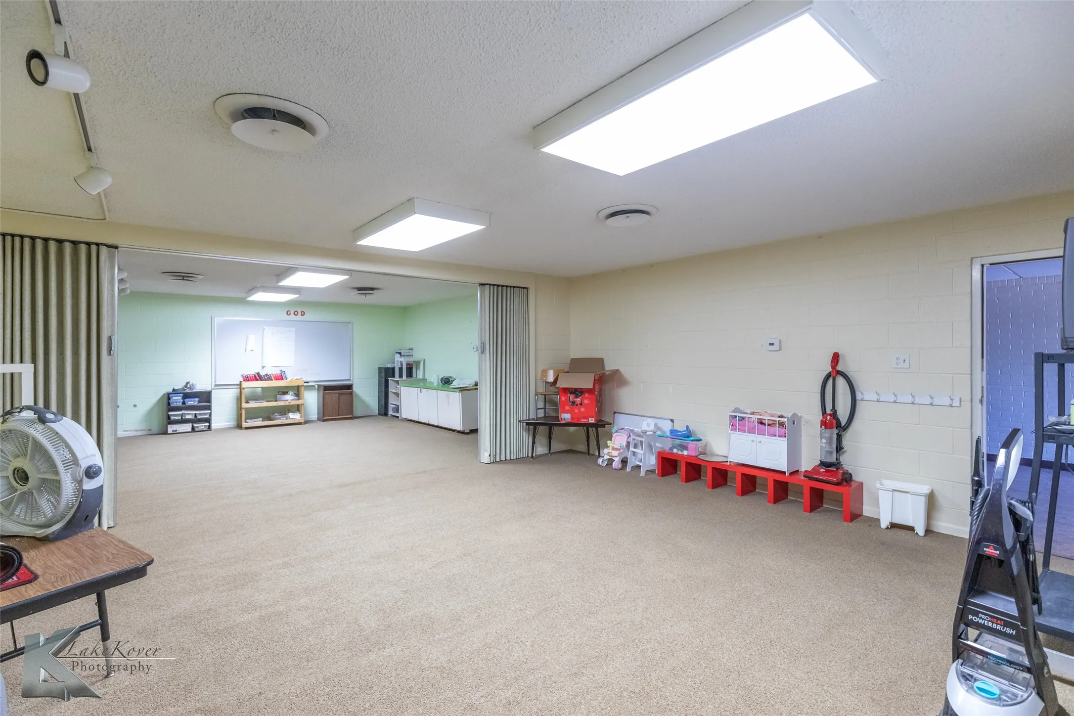 Playroom with concrete block wall, a textured ceiling, and light carpet