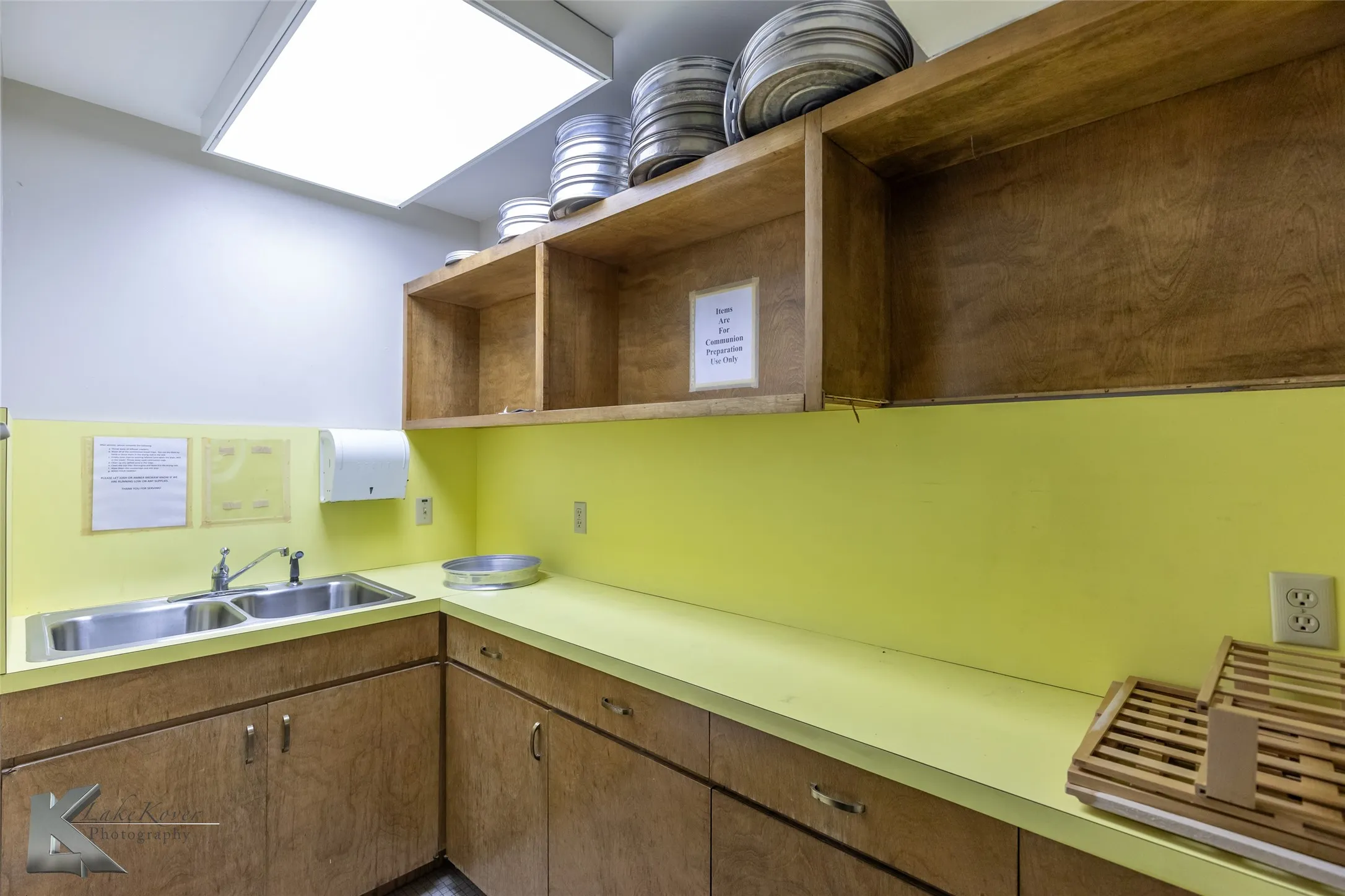 Kitchen with open shelves, brown cabinets, and light countertops