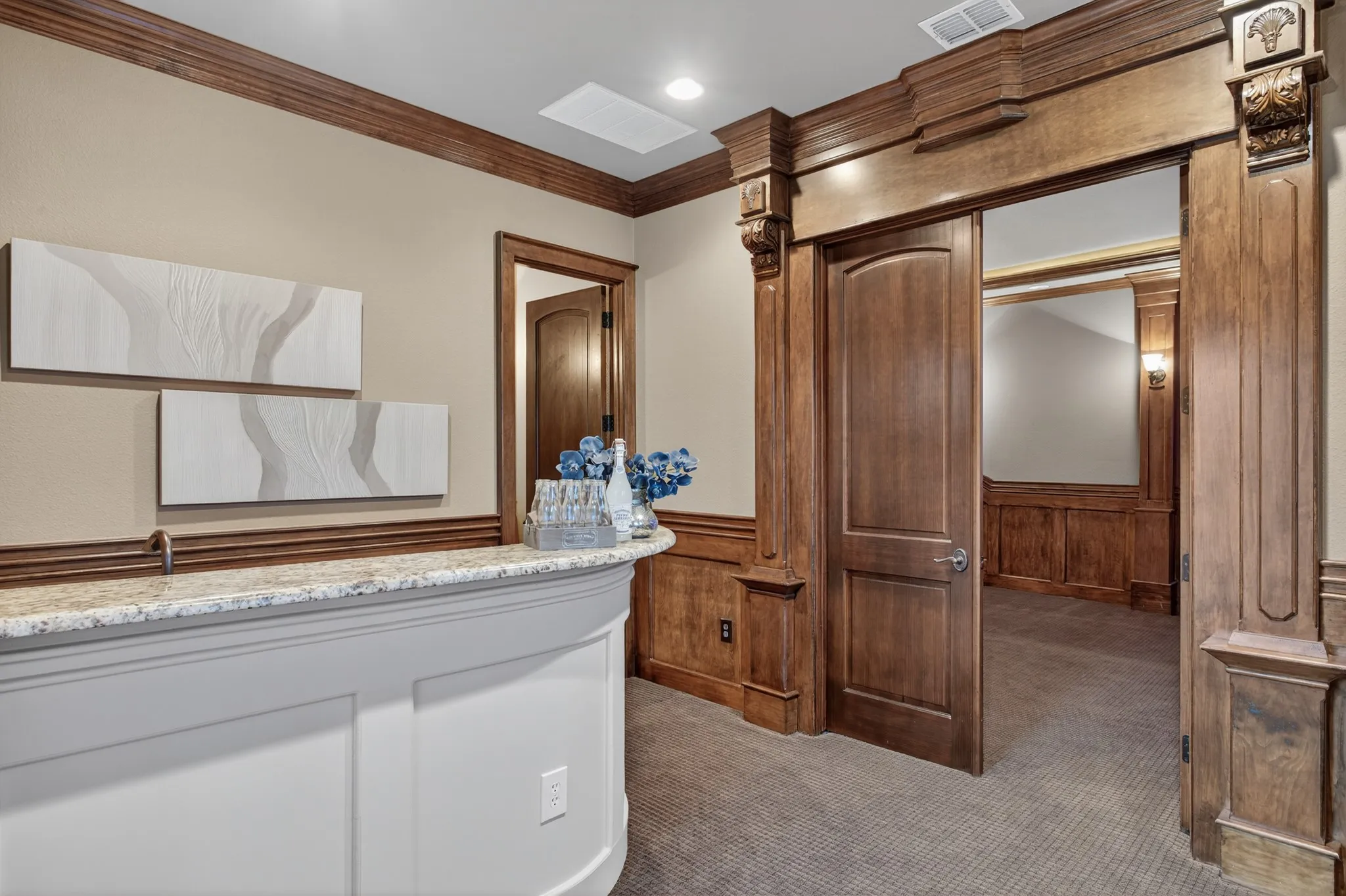Step into the ultimate cinematic retreat through this elegant entryway, where rich wood millwork and stately columns set the tone for a true luxury experience. A granite-topped bar—complete with a built-in fridge—offers the perfect place to prepare drinks and snacks before showtime. When it's time for the film to begin, close the beautifully crafted double privacy doors and immerse yourself in an authentic theater experience, all from the comfort of your own upstairs oasis.