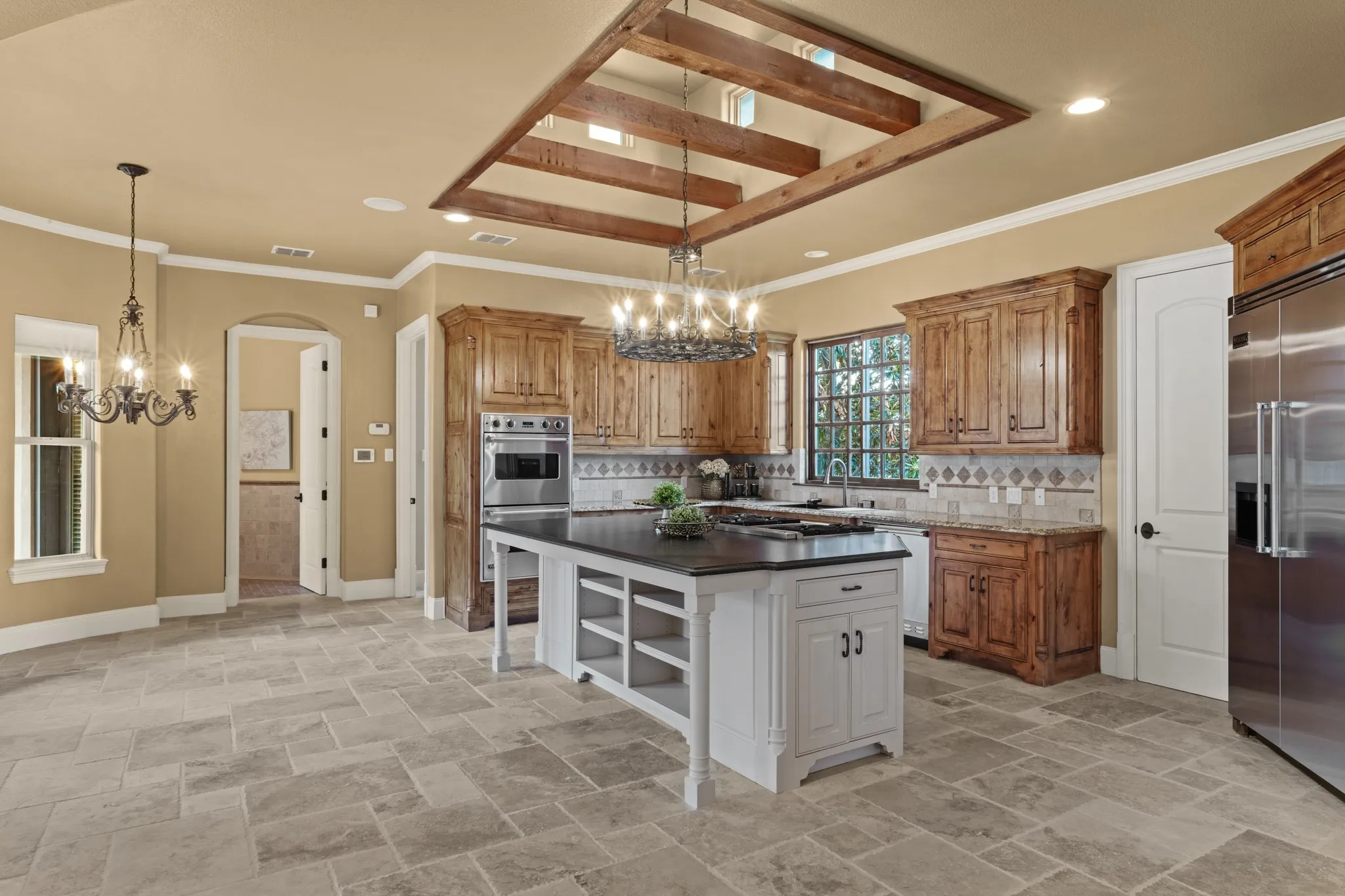A true chef’s dream, this stunning kitchen features top-of-the-line stainless steel appliances, rich granite countertops, and a distinctive raised ceiling adorned with warm cedar beams. Elevated windows bring in an abundance of natural light, while the architectural details beautifully echo the home’s Tuscan-inspired design, creating a seamless blend of rustic charm and modern sophistication.