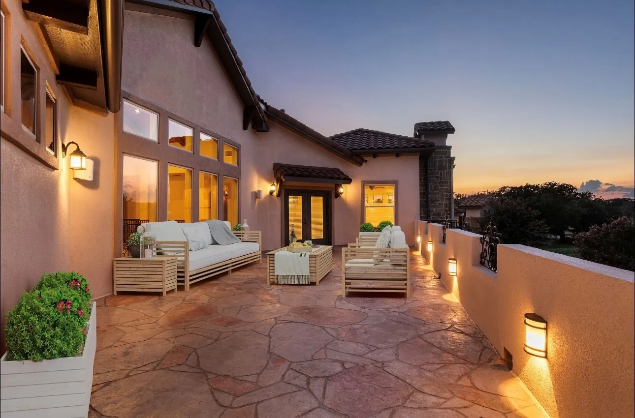 This expansive stone-tiled terrace is a true extension of the home's luxury living, offering panoramic views of the resort-style pool, spa, and cascading waterfall, all set against the backdrop of a tree-lined 2-acre estate. Thoughtfully designed accent lighting creates a warm ambiance for evening entertaining or quiet starlit retreats. Whether you’re hosting sunset soirees or enjoying morning coffee in solitude, this elevated outdoor haven offers the perfect vantage point to take in the natural beauty and serenity that surrounds this remarkable property.