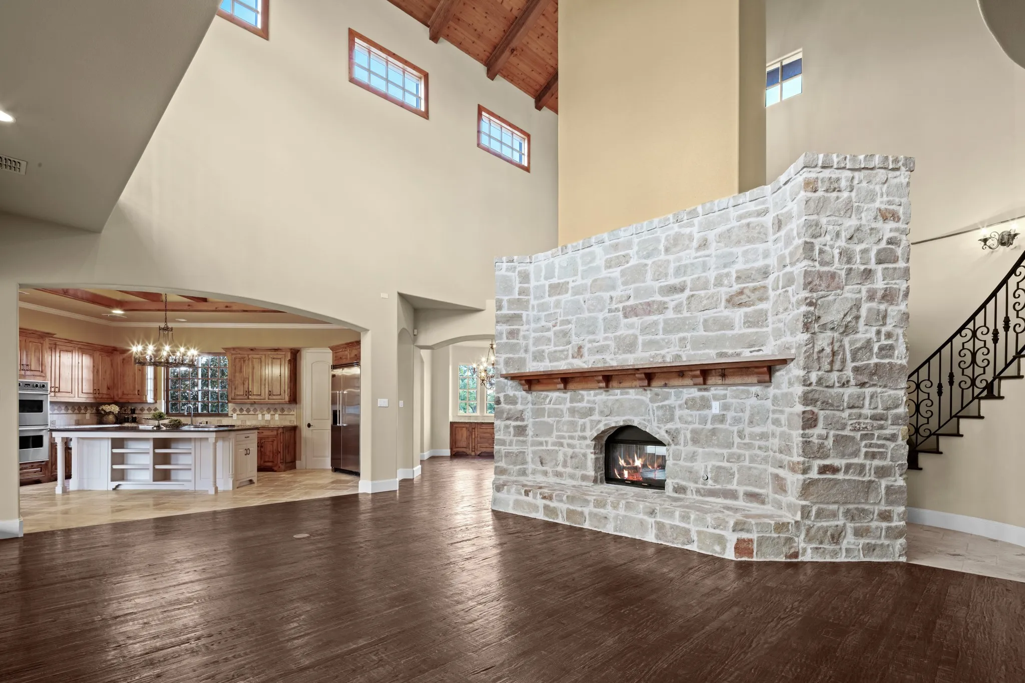 This captivating view of the living area highlights the exquisite craftsmanship of the stone fireplace, a true architectural masterpiece and commanding focal point, while the soaring vaulted wood ceiling adds warmth, grandeur, and timeless character to the space.