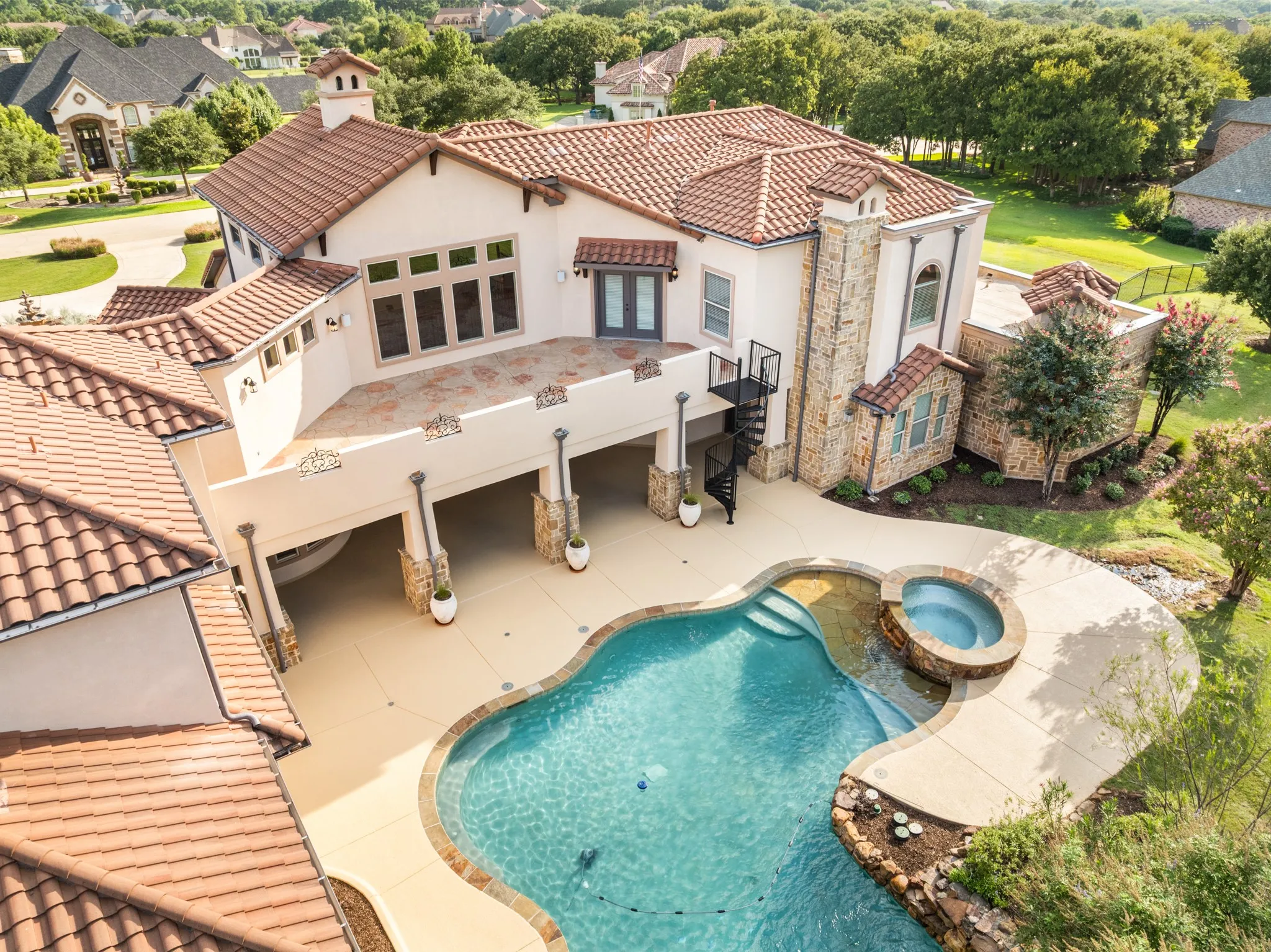 Step into a private resort-style retreat designed for both relaxation and grand-scale entertaining. A sparkling custom pool takes center stage, complete with an integrated spa, cascading waterfall, and a generous tanning ledge. The expansive upper terrace offers panoramic views of the backyard oasis and seamlessly connects to a spacious covered patio below—ideal for outdoor dining or lounging in the shade. Extensive pool decking provides plenty of space for sunbathing, social gatherings, or hosting unforgettable poolside parties. Surrounded by mature trees and pristine landscaping, this outdoor haven offers serenity, privacy, and sophistication—all nestled on over 2 acres in one of Flower Mound’s most prestigious gated communities.