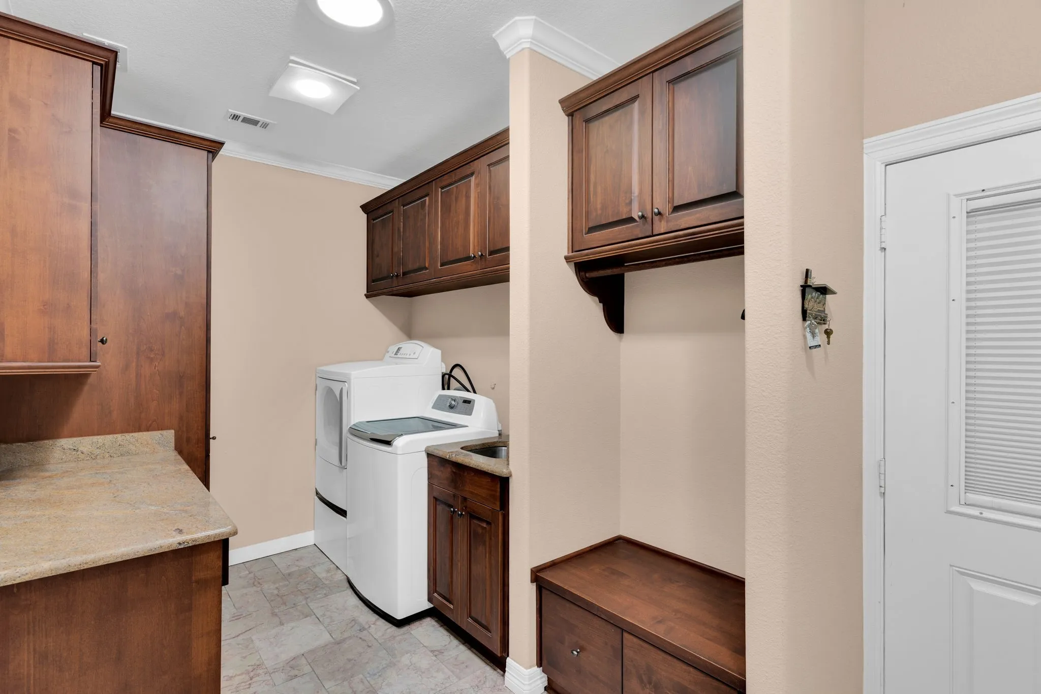 Laundry room featuring crown molding, stone finish flooring, washing machine and dryer, and cabinet space