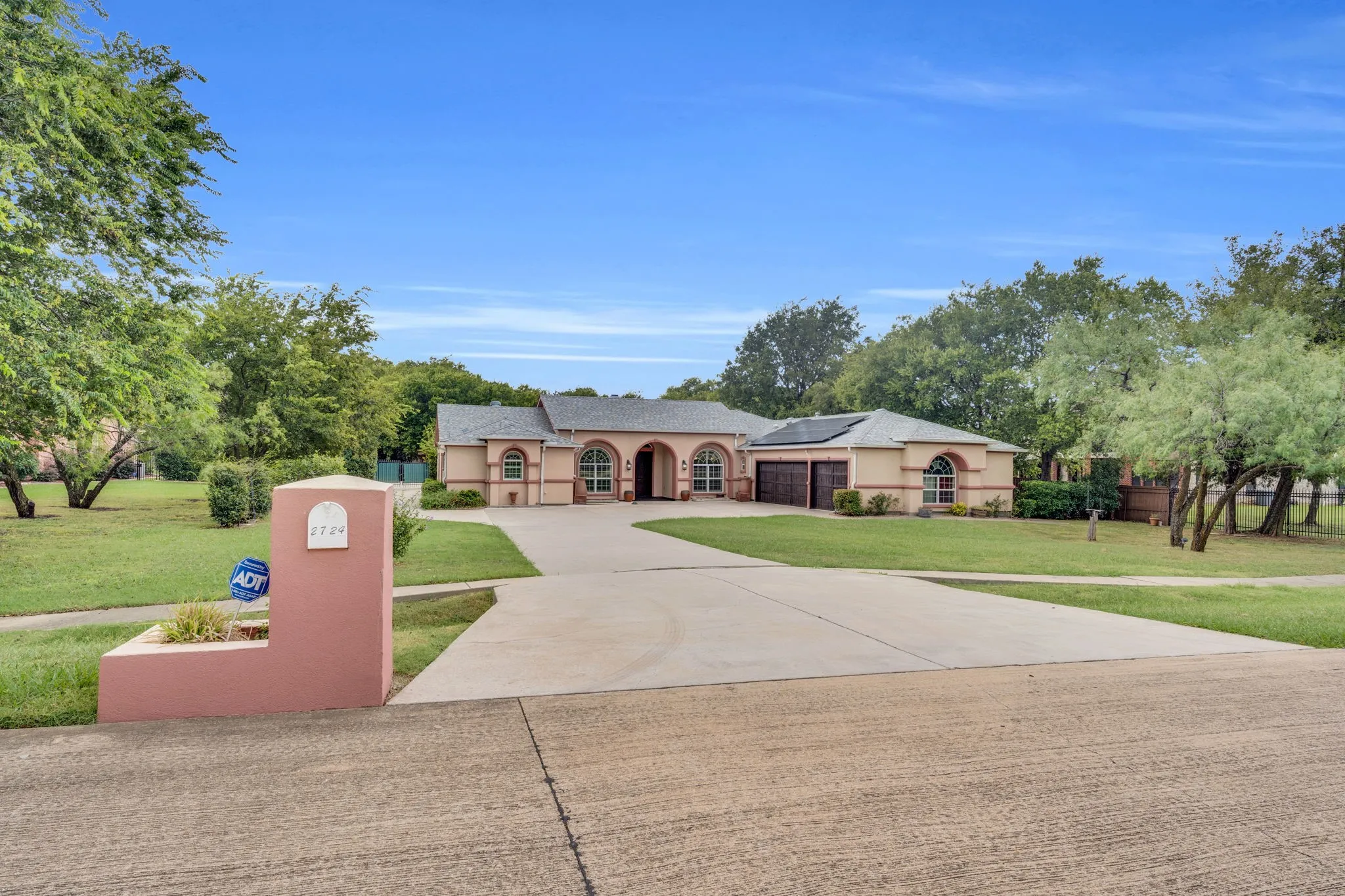 Mediterranean / spanish home featuring concrete driveway, a front yard, stucco siding, and roof mounted solar panels