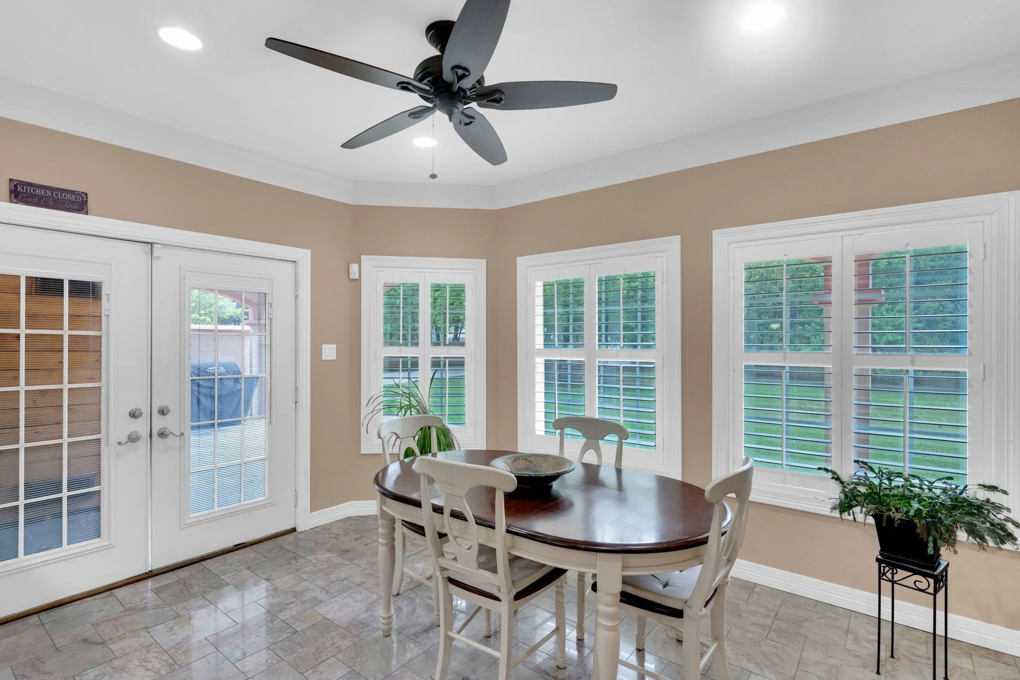 Dining space featuring french doors, crown molding, light stone finish floors, recessed lighting, and ceiling fan