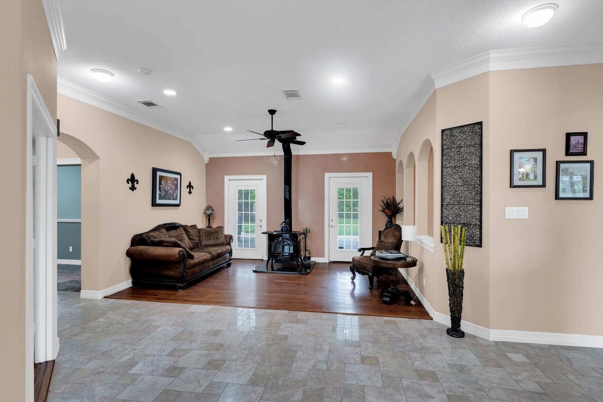 Living room with arched walkways, crown molding, recessed lighting, a wood stove, and stone finish floors