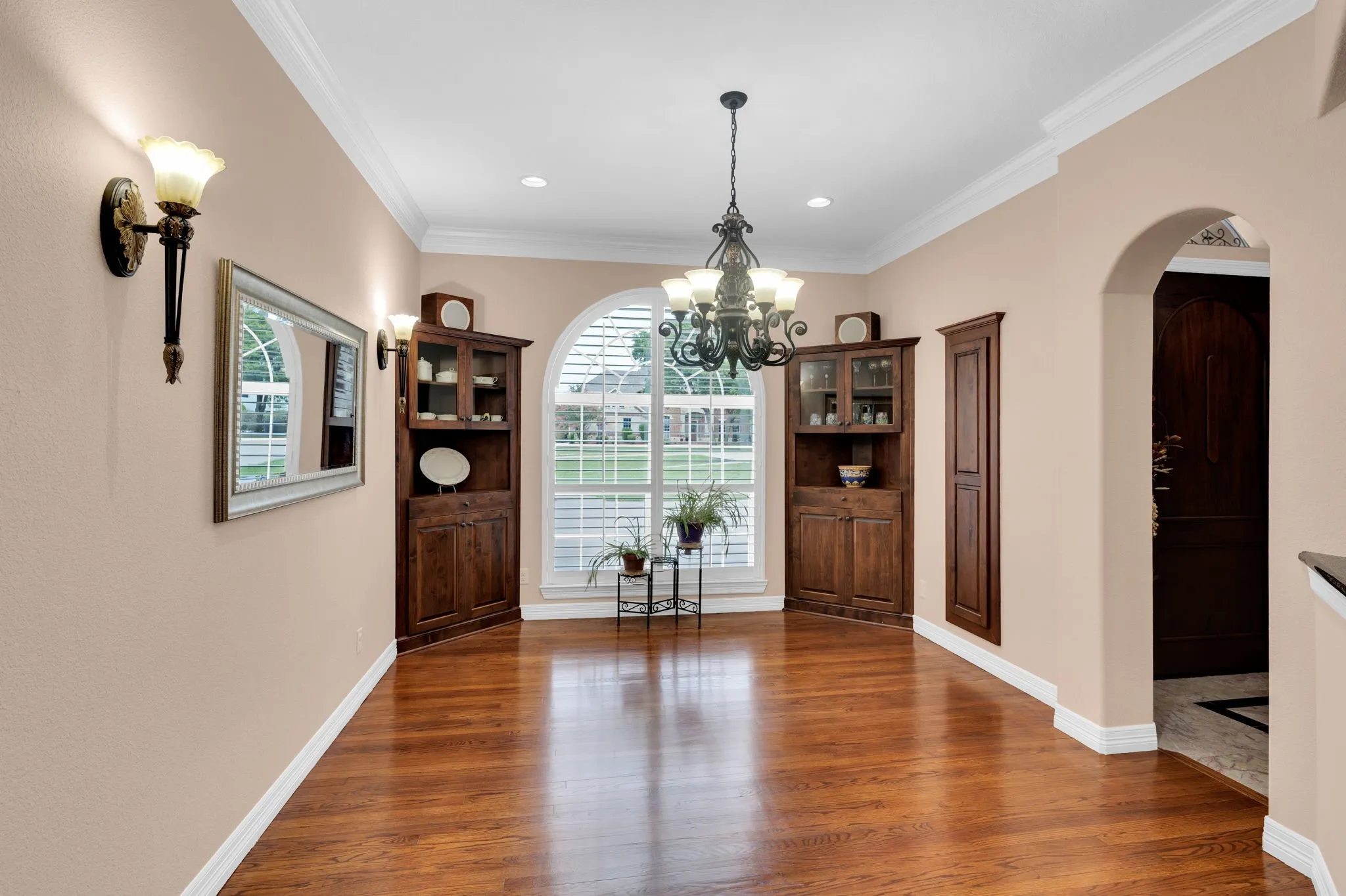Dining area featuring crown molding, arched walkways, dark wood-style flooring, a chandelier, and recessed lighting