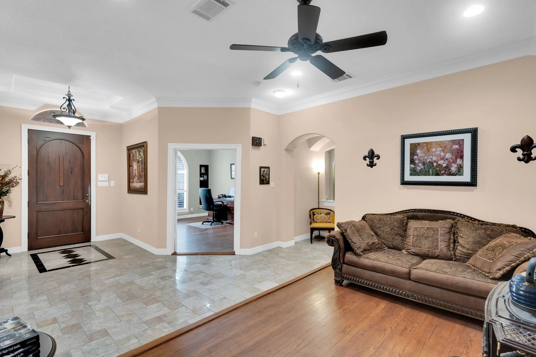 Living area featuring crown molding, an office area, light wood-style floors, and arched walkways