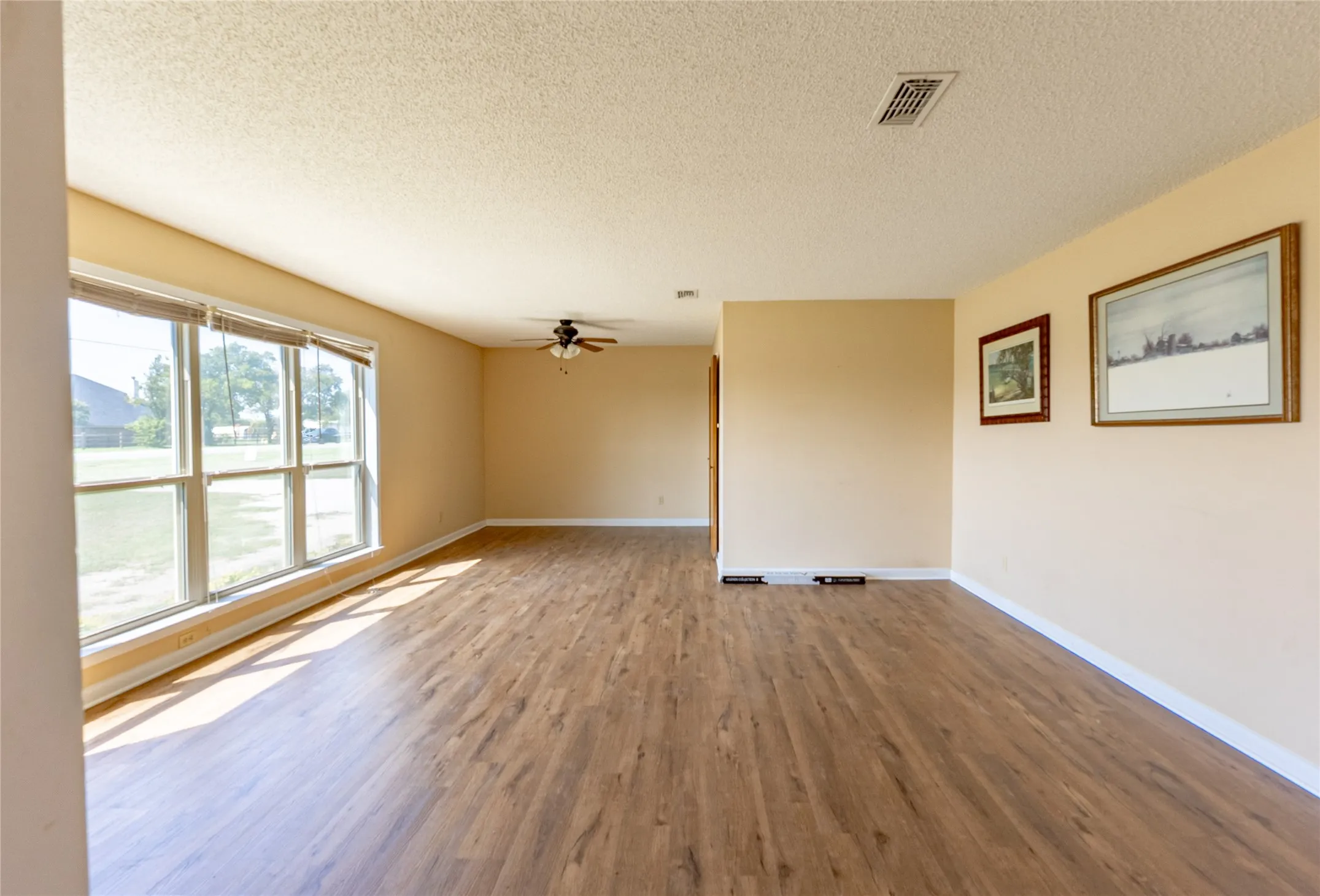 Unfurnished room with a textured ceiling, wood finished floors, and ceiling fan