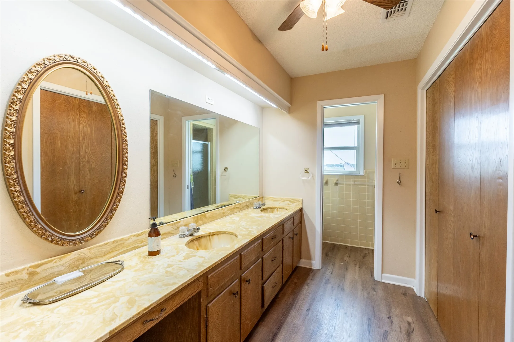 Bathroom with dark wood-style flooring, double vanity, and ceiling fan