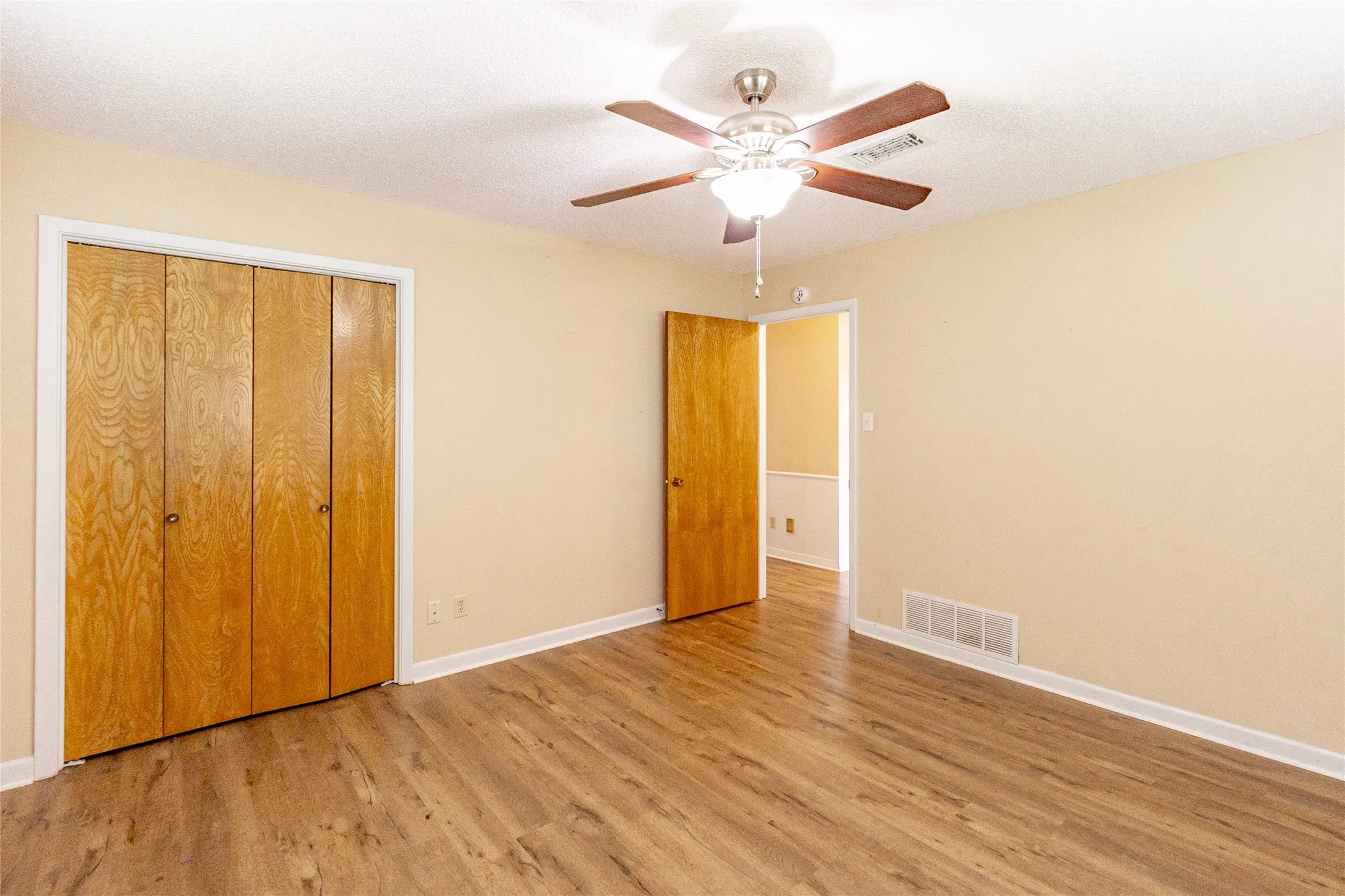 Unfurnished bedroom with wood finished floors, a closet, a textured ceiling, and a ceiling fan