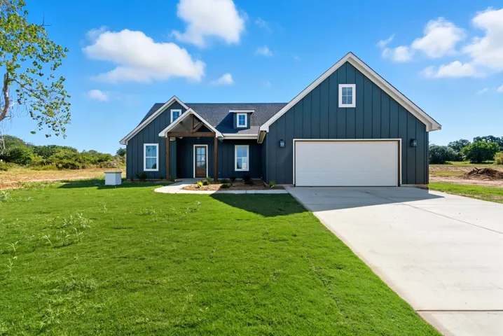 Modern farmhouse with board and batten siding, driveway, and a front yard