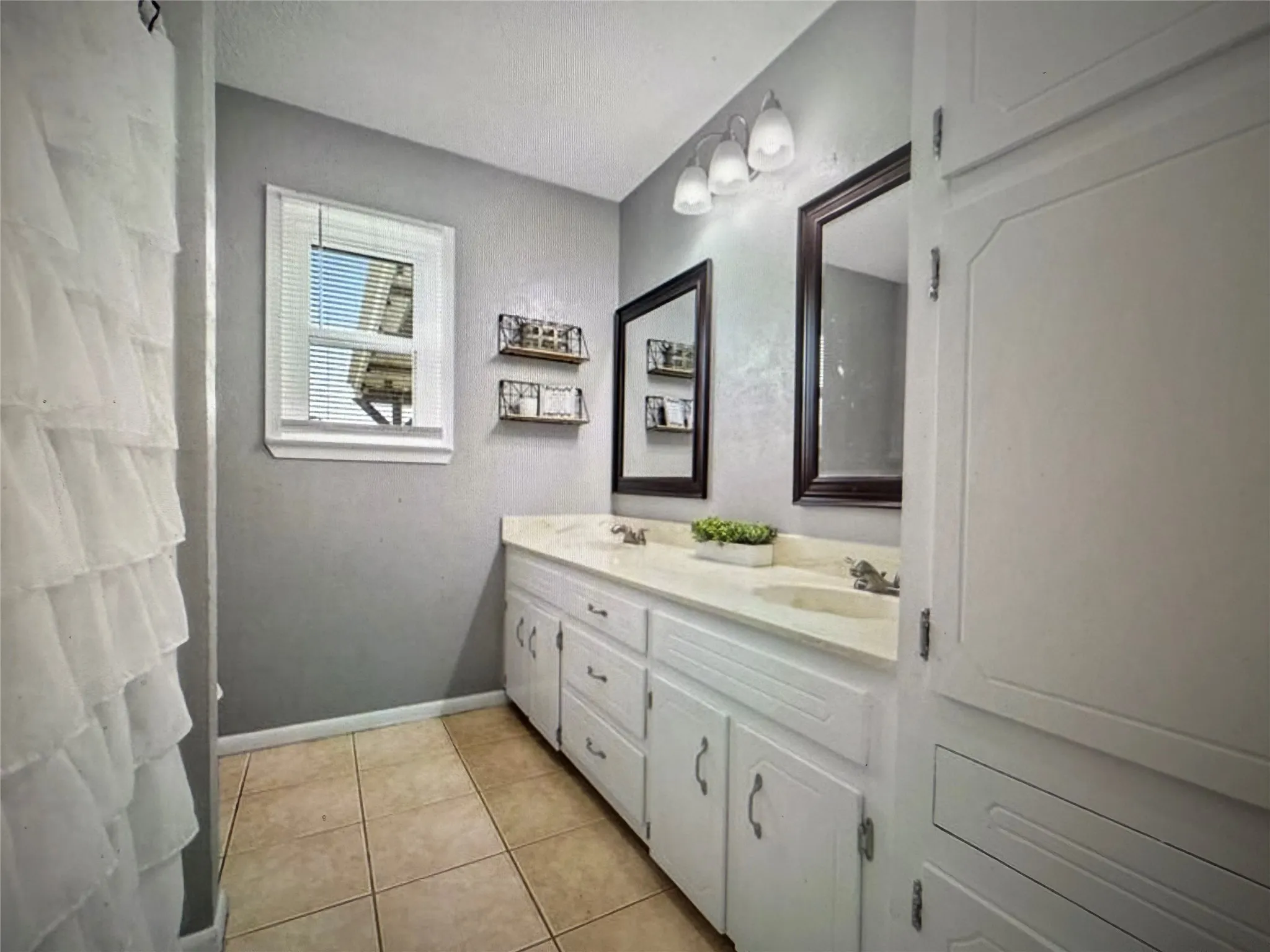 Full bathroom with double vanity and light tile patterned floors
