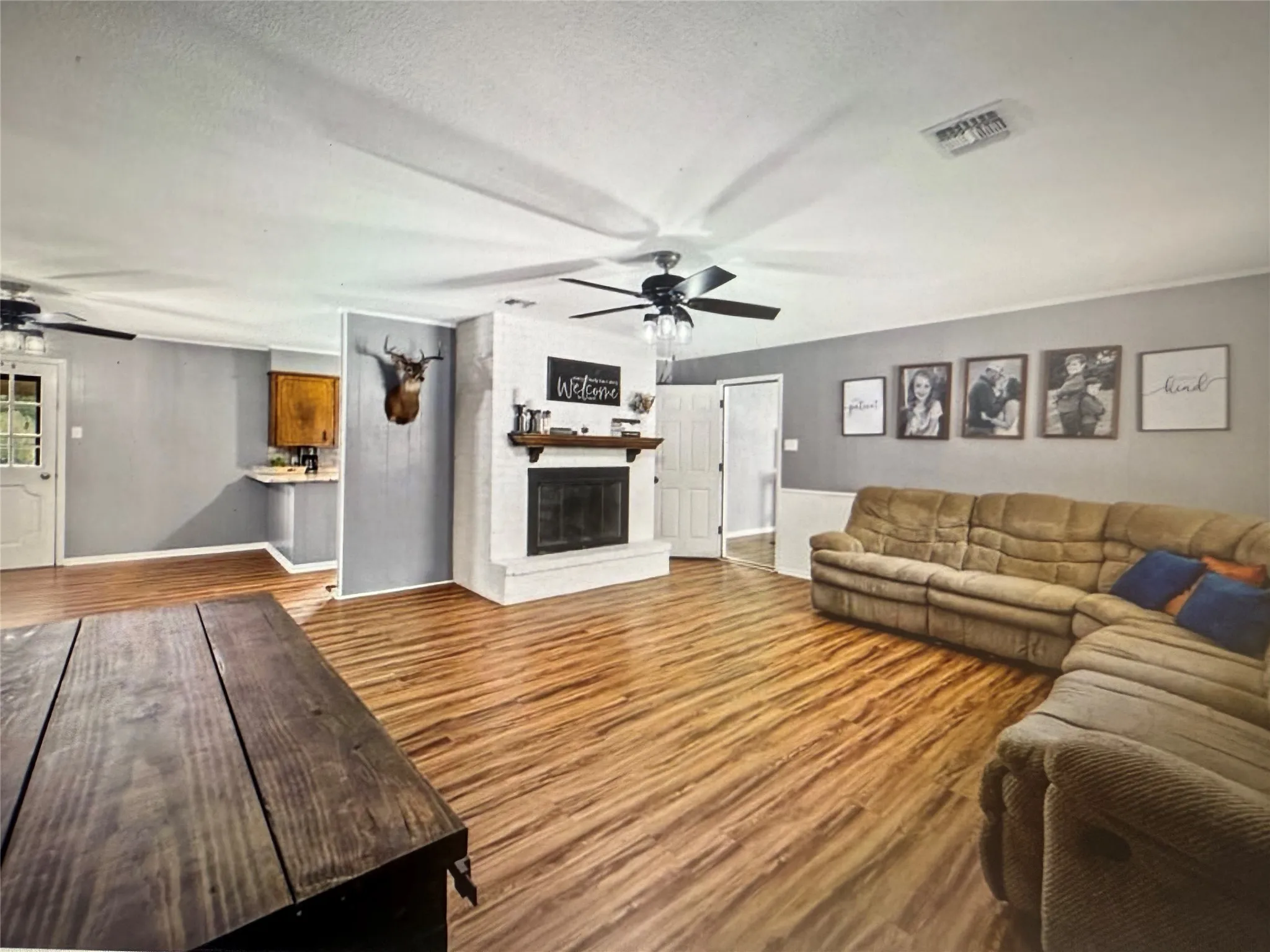 Living area featuring a ceiling fan, wood finished floors, a textured ceiling, and a large fireplace